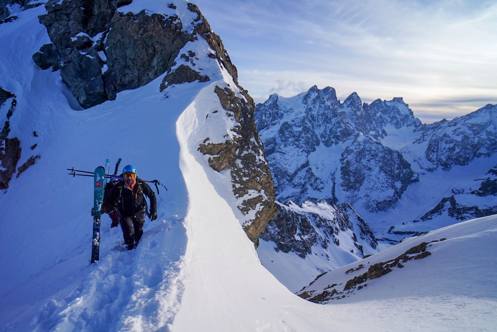 Skieur skis sur le sac, en progression sur une crête enneigée au-dessus d'un vallon glaciaire, Tour des Agneaux (Écrins)