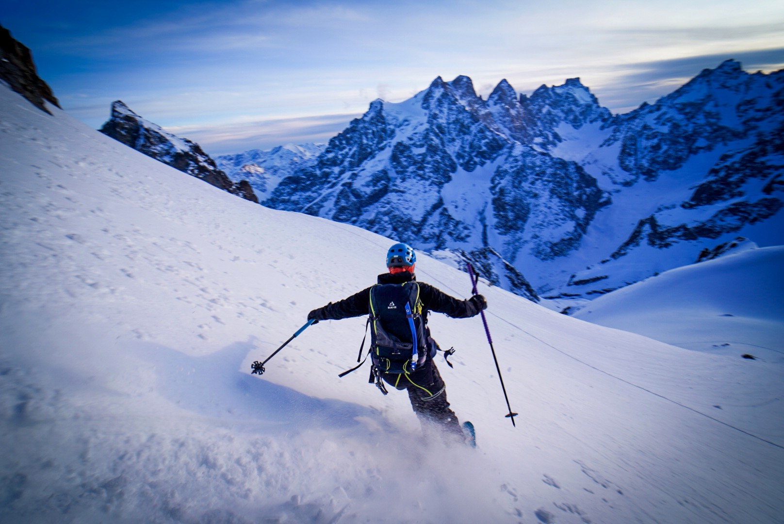 Skieur descendant une pente de neige poudreuse devant un massif de sommets glaciaires, Tour des Agneaux (Écrins)