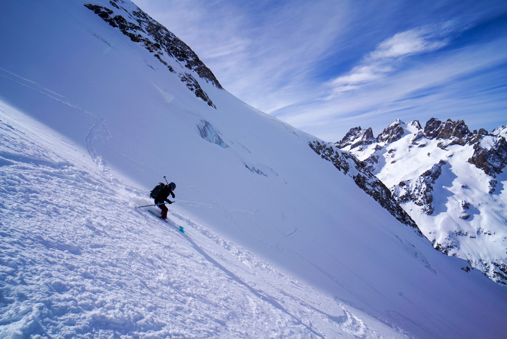 Skieur en descente sur une pente de neige, une crête rocheuse sur la droite, Tour des Agneaux (Écrins)