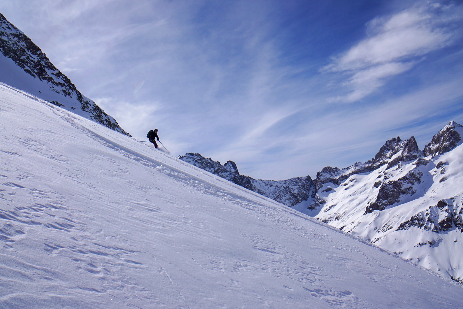 Skieur en descente sur une pente enneigée, au loin une crête rocheuse, Tour des Agneaux (Écrins)