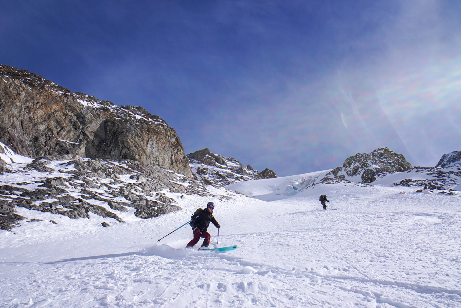 Skieur en descente près d'une barre rocheuse, ciel bleu, Tour des Agneaux (Écrins)