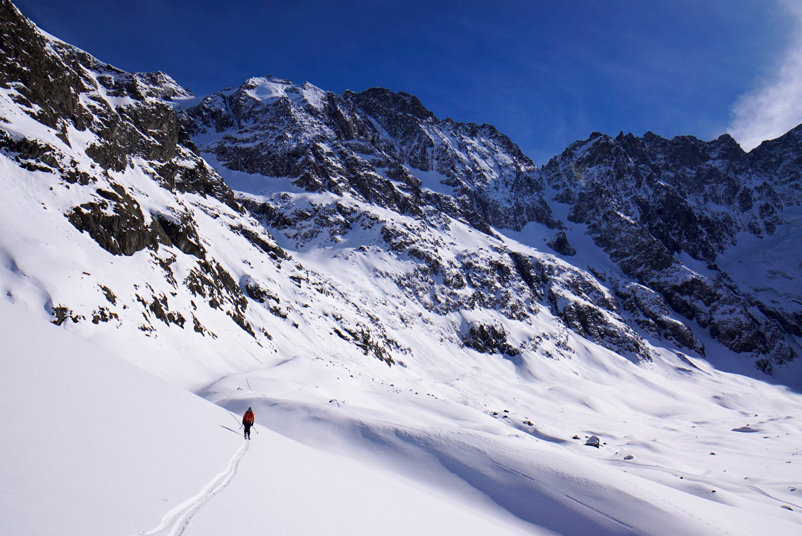 Skieur isolé en contrebas d'une grande paroi enneigée, au fond d'un vallon des Écrins, Tour des Agneaux