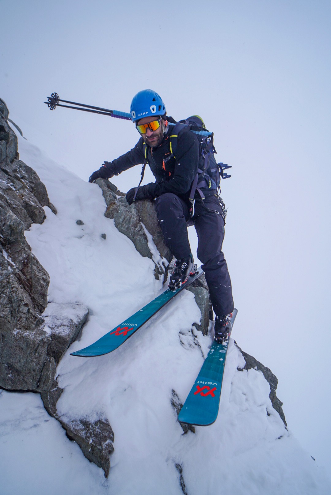 Skieur franchissant un passage rocheux raide, skis aux pieds, dans la brume, Tour des Agneaux (Écrins)