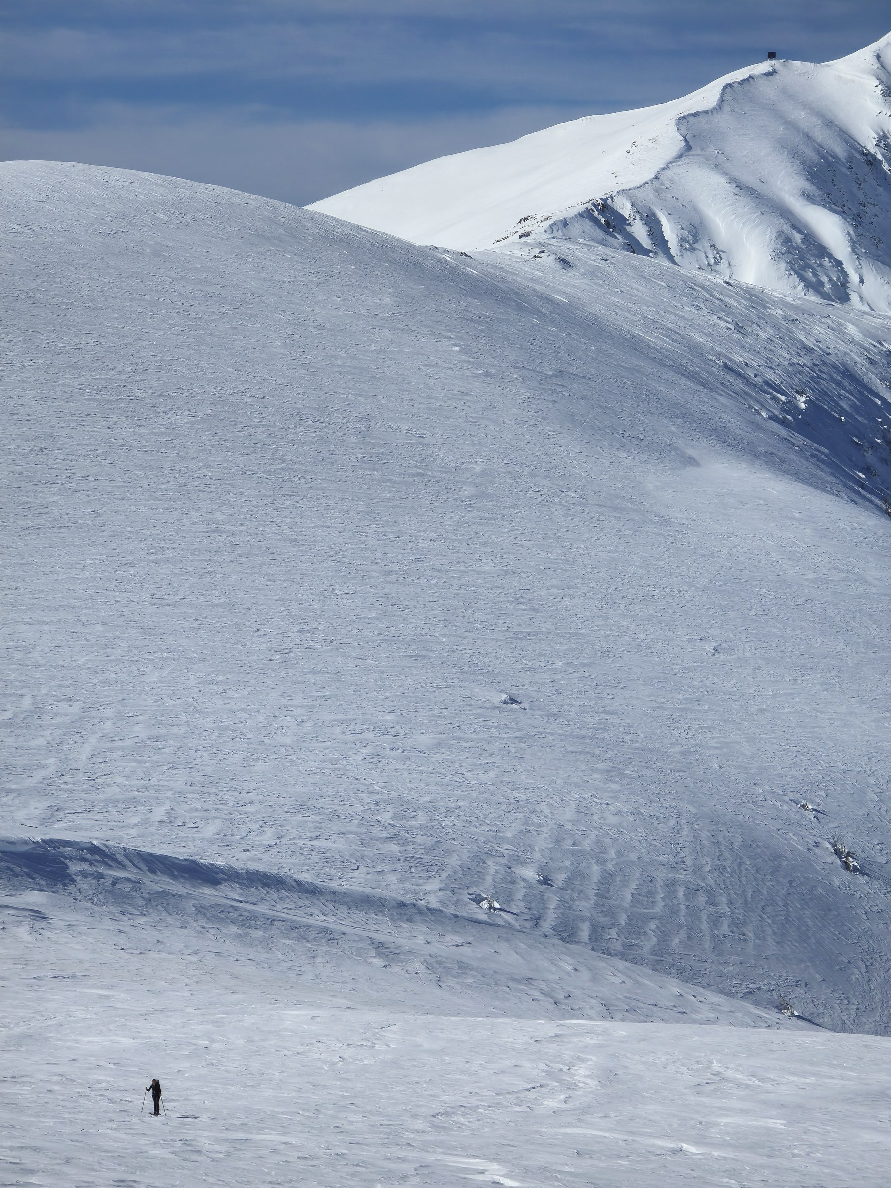 Skieur solitaire sur un plateau pendant la traversée à ski des Alpes ligures, au jour 5 de l’itinérance.