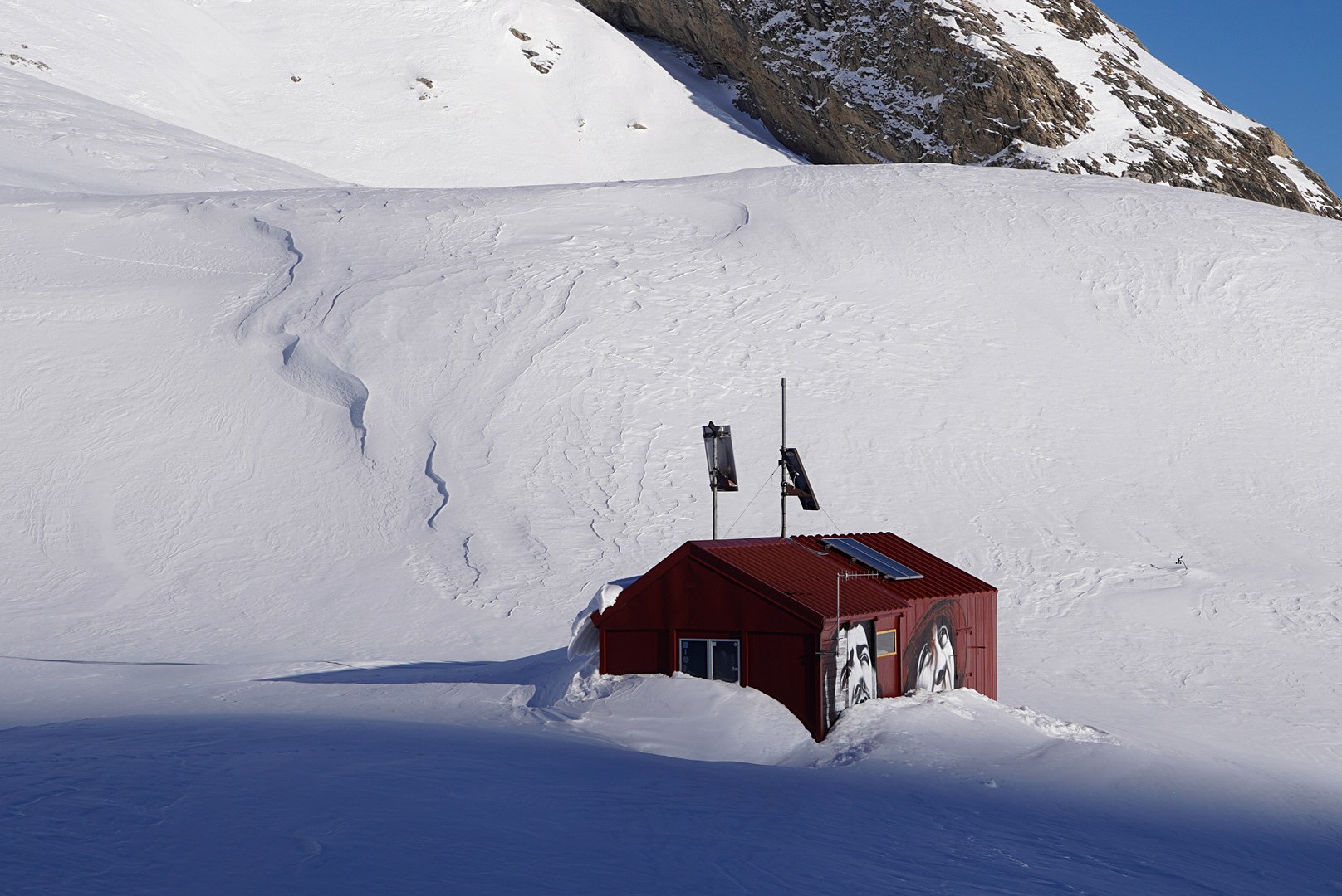 Petite cabane rouge dans la neige pendant la traversée à ski des Alpes ligures, au jour 2 de l’itinérance.