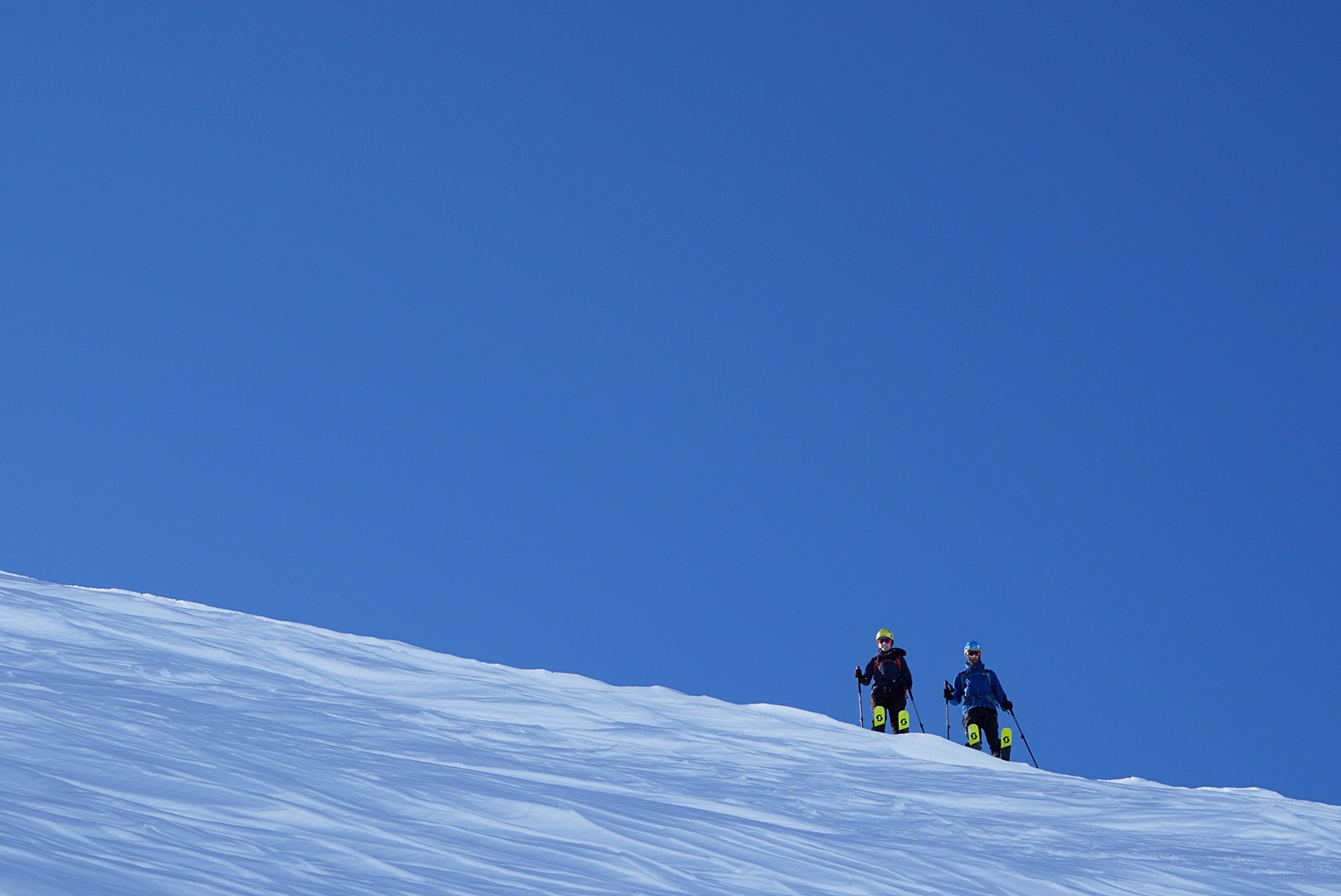Deux skieurs apparaissant derrière une bosse pendant la traversée à ski des Alpes ligures, au jour 3 de l’itinérance.