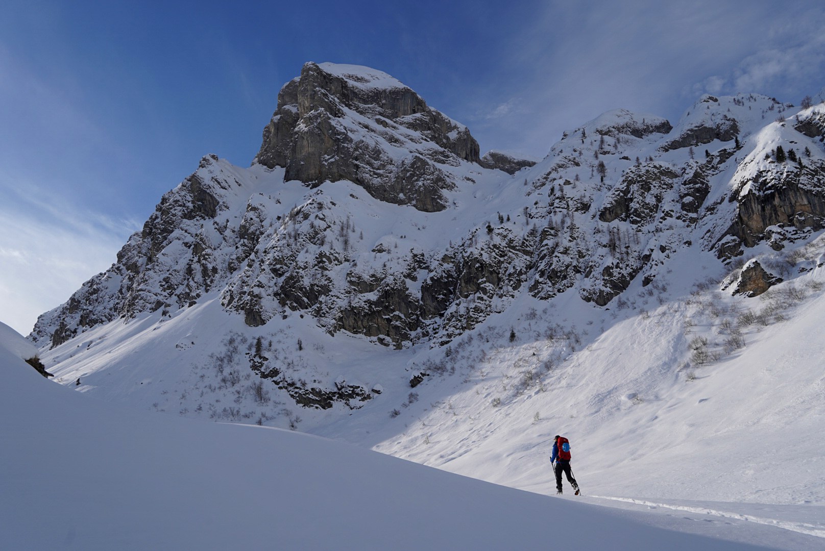 Skieur au pied d’une grande paroi pendant la traversée à ski des Alpes ligures, au jour 4 de l’itinérance.