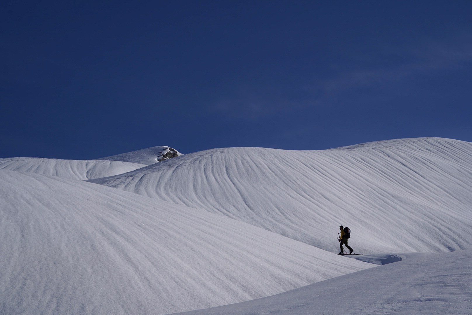 Progression sur une neige travaillée par le vent pendant la traversée à ski des Alpes ligures, au jour 4 de l’itinérance.