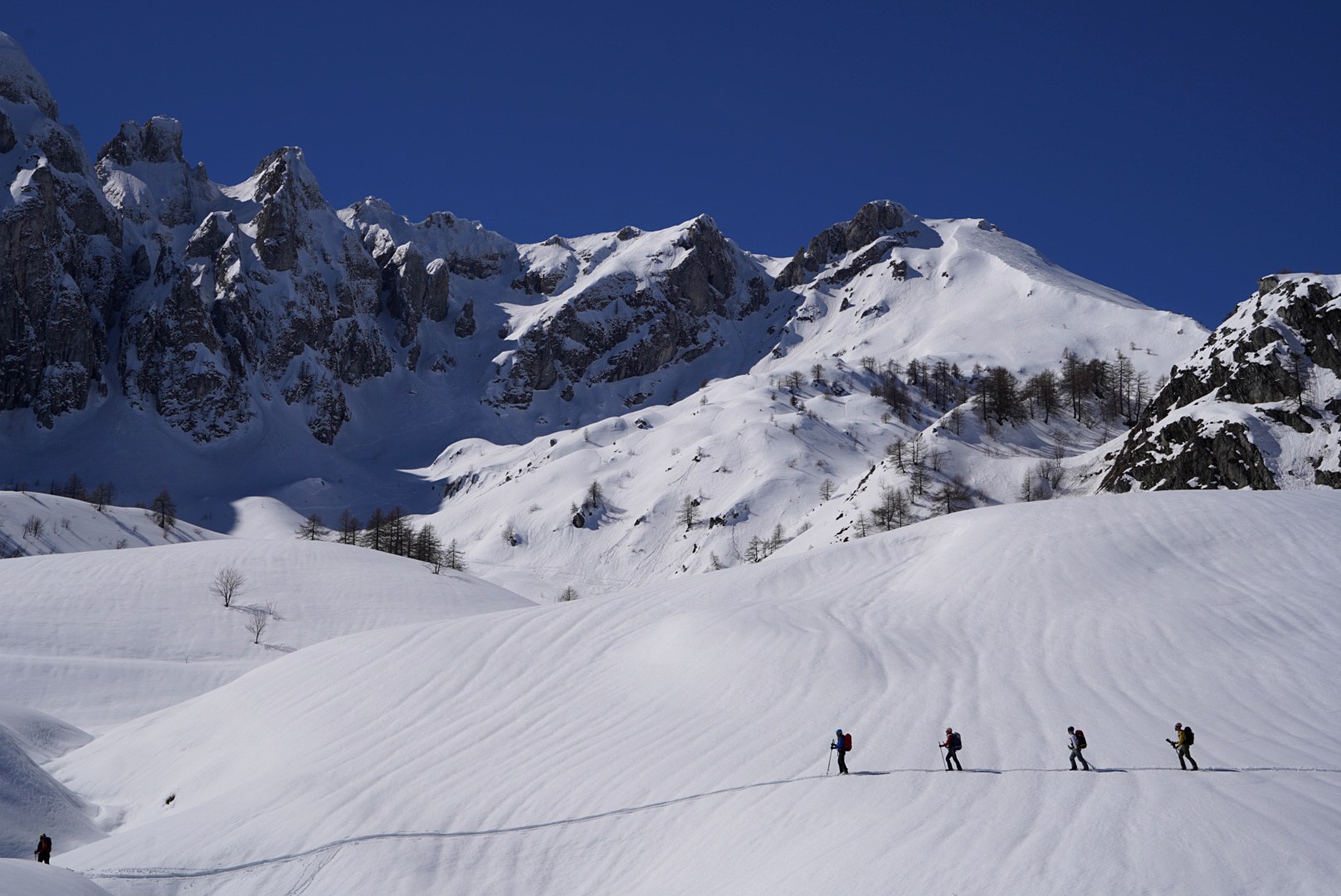 Longue traversée du groupe sous les parois pendant la traversée à ski des Alpes ligures, au jour 5 de l’itinérance.