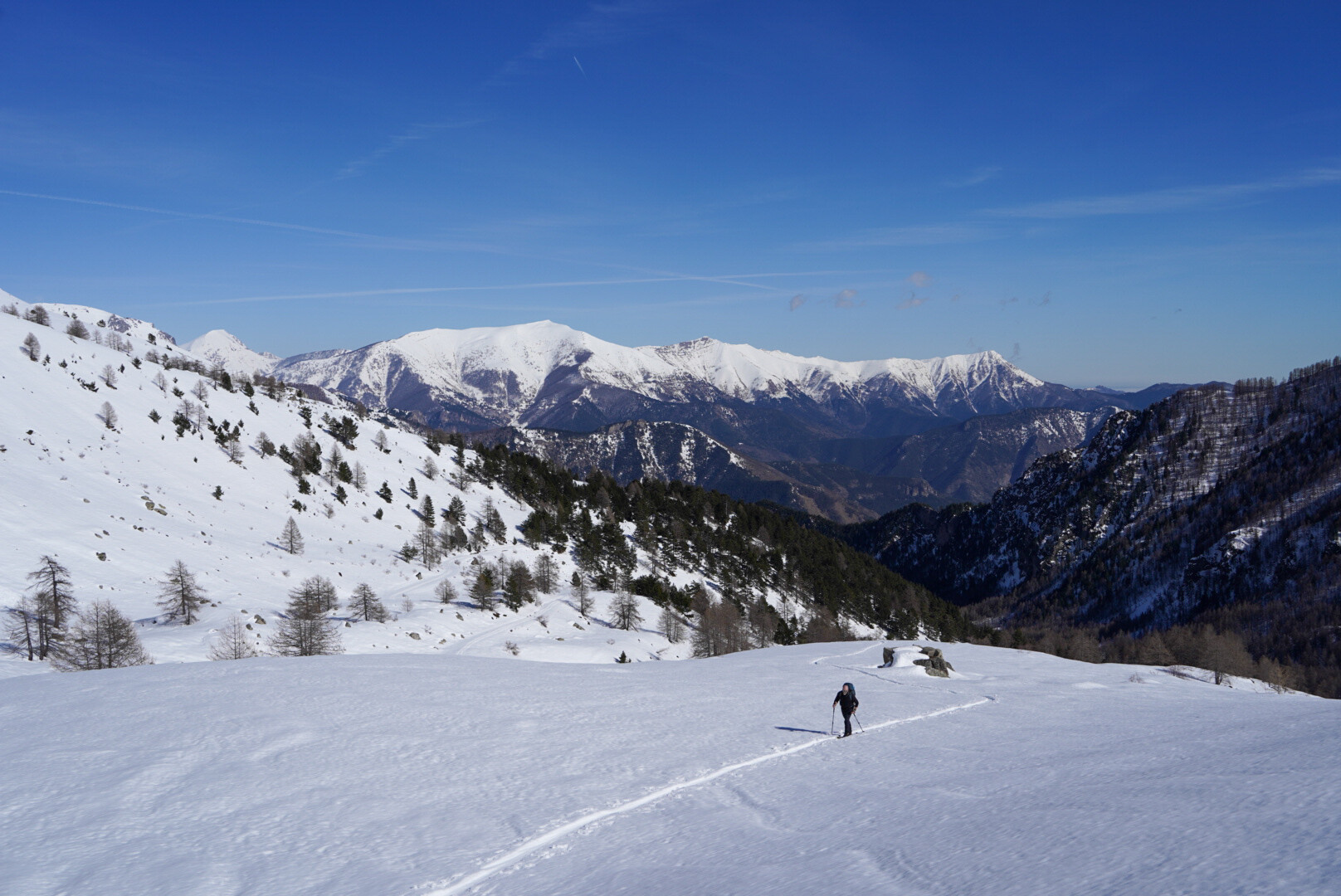 skieur de randonnée en ascension sous un sommet rocheux