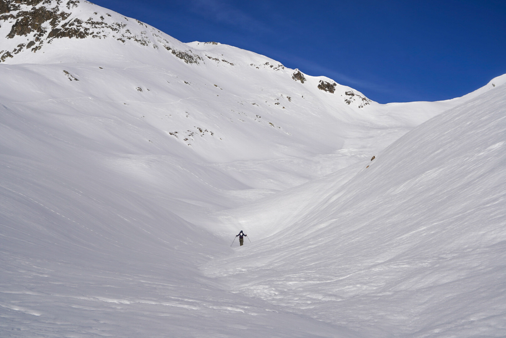 skieurs de randonnée en montée sous une paroi rocheuse enneigée