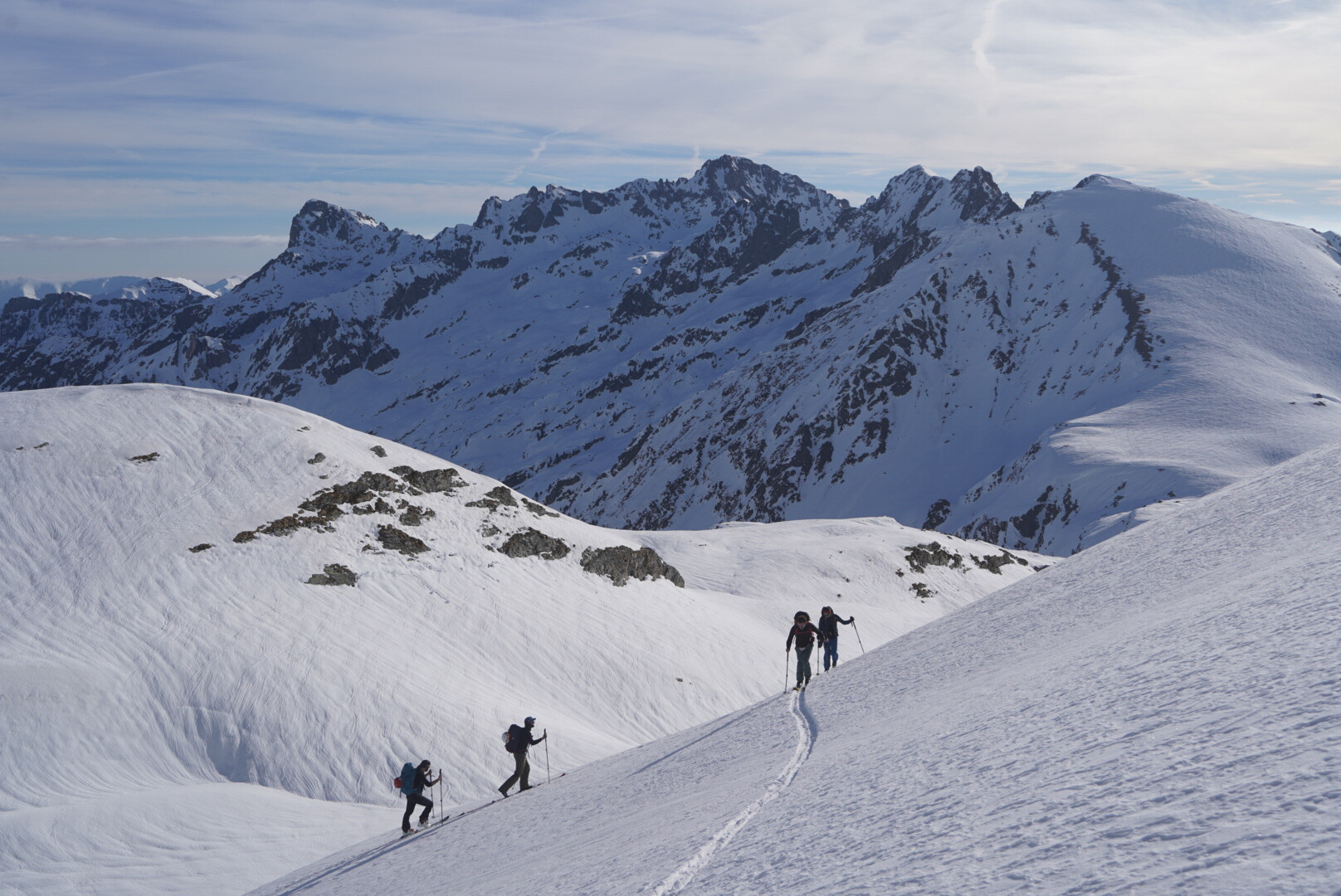 groupe de skieurs de randonnée traversant un large vallon enneigé