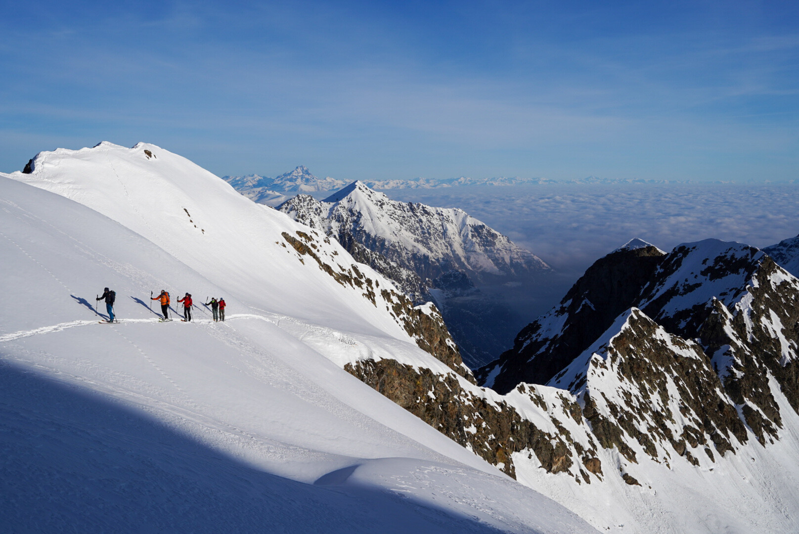 deux skieurs de randonnée traversant un vallon enneigé, sacs sur le dos