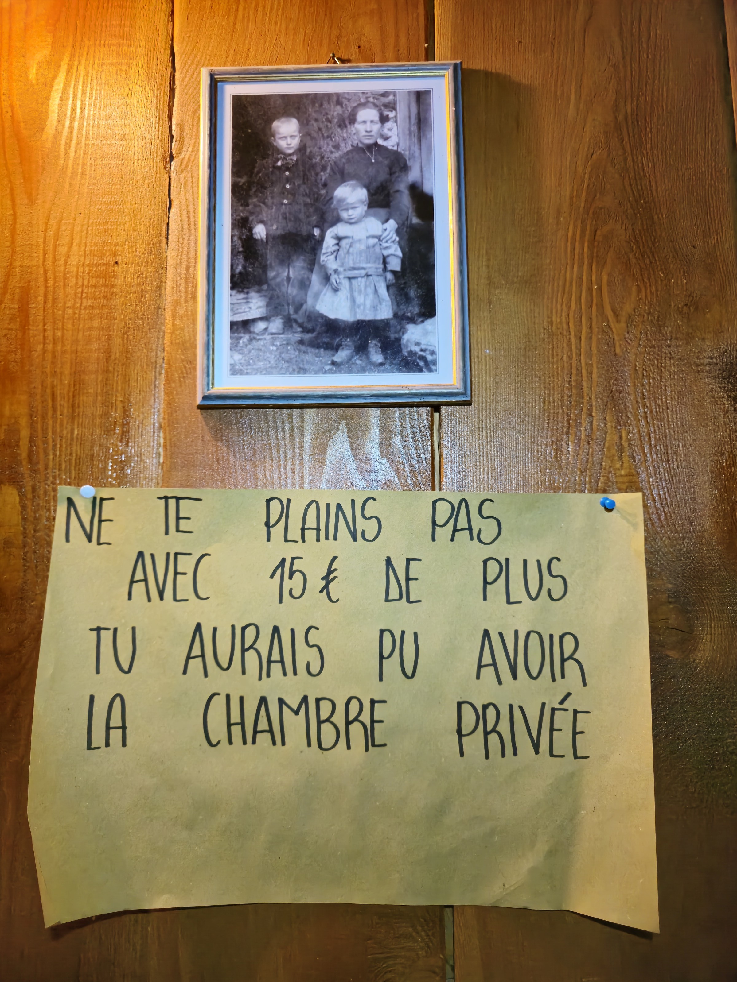 mot manuscrit humoristique punaisé au mur d'une chambre de refuge
