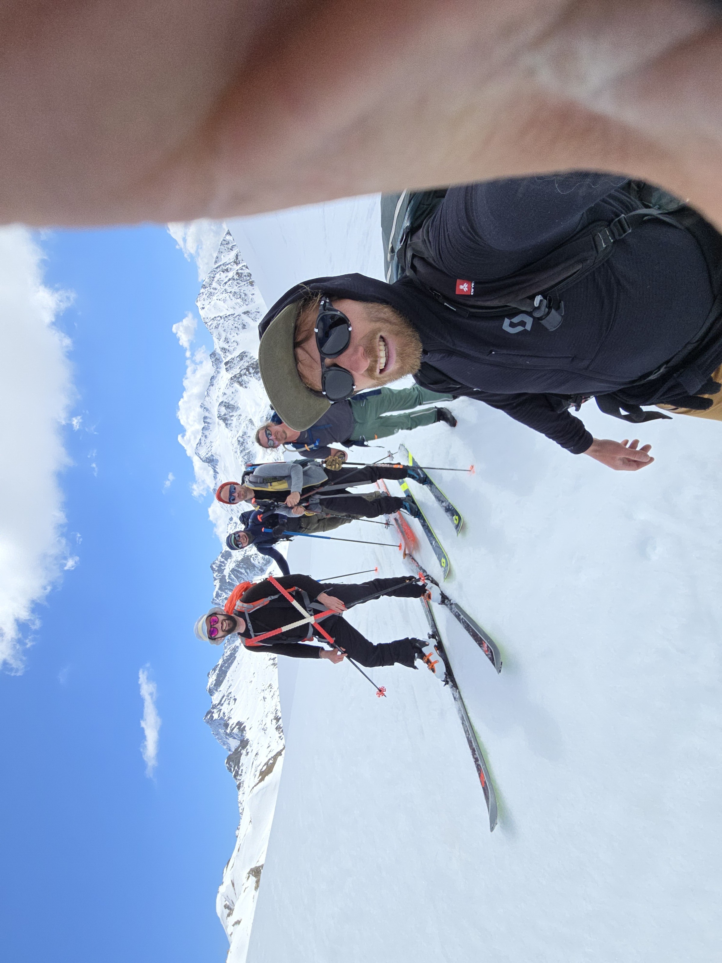 deux skieurs de randonnée souriant en gros plan, skis sur l'épaule