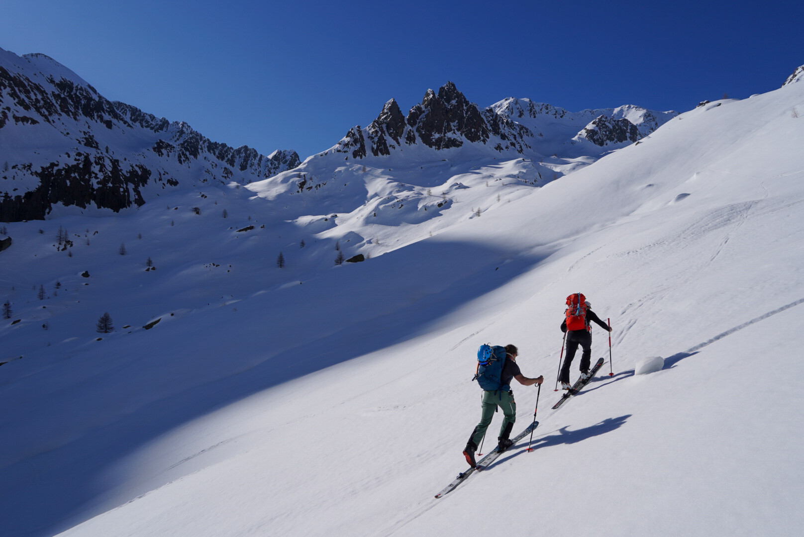 trois skieurs de randonnée au sommet, skis levés en signe de victoire