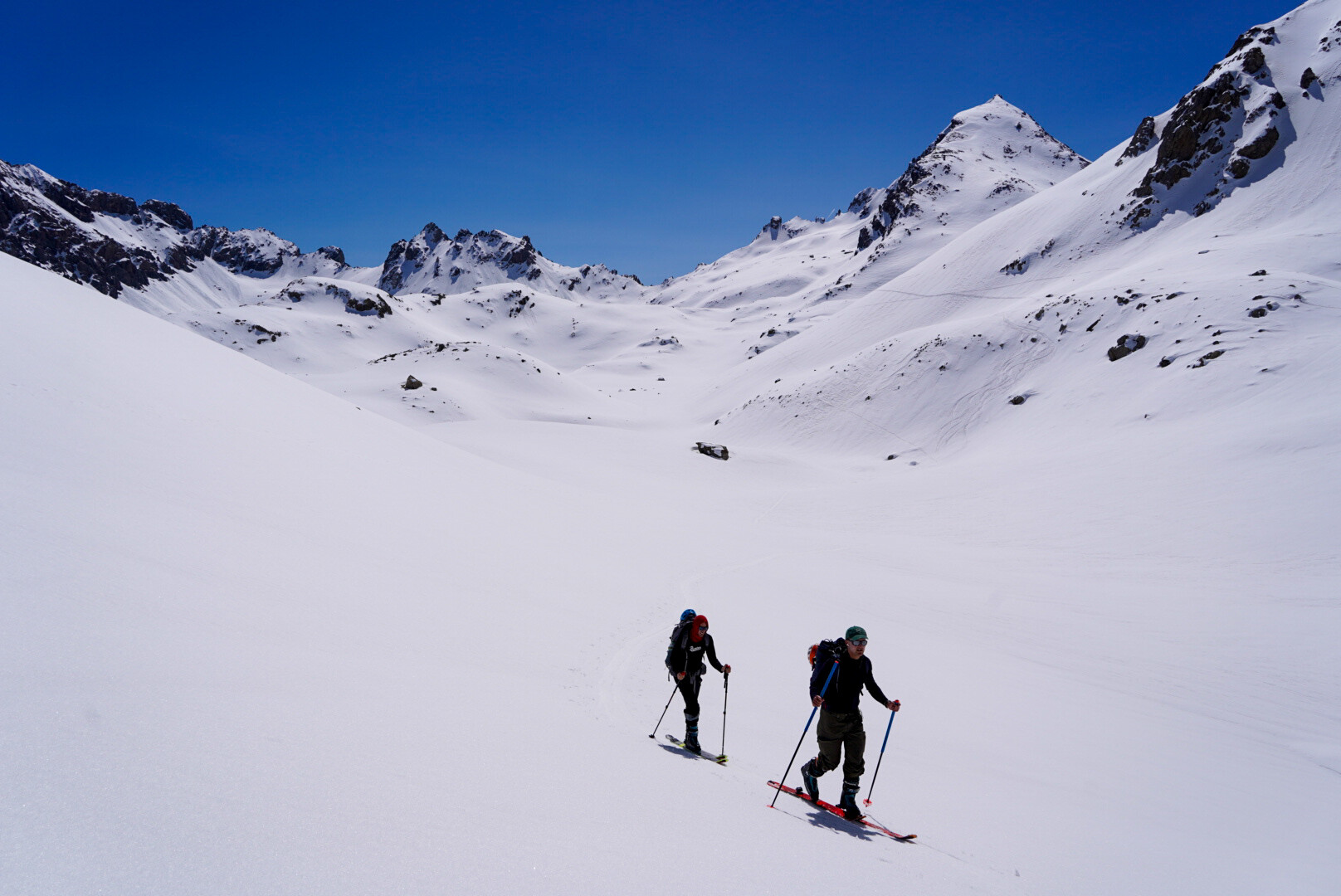 deux skieurs de randonnée progressant vers un sommet dans la lumière du matin