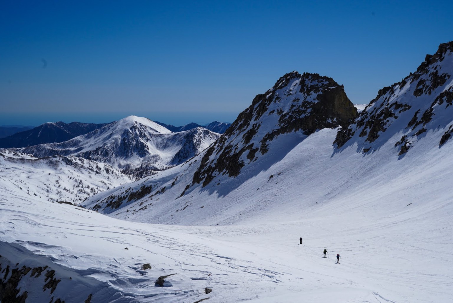 Skieurs de randonnée dans les grands espaces du massif de l'Argentera, mer en toile de fond