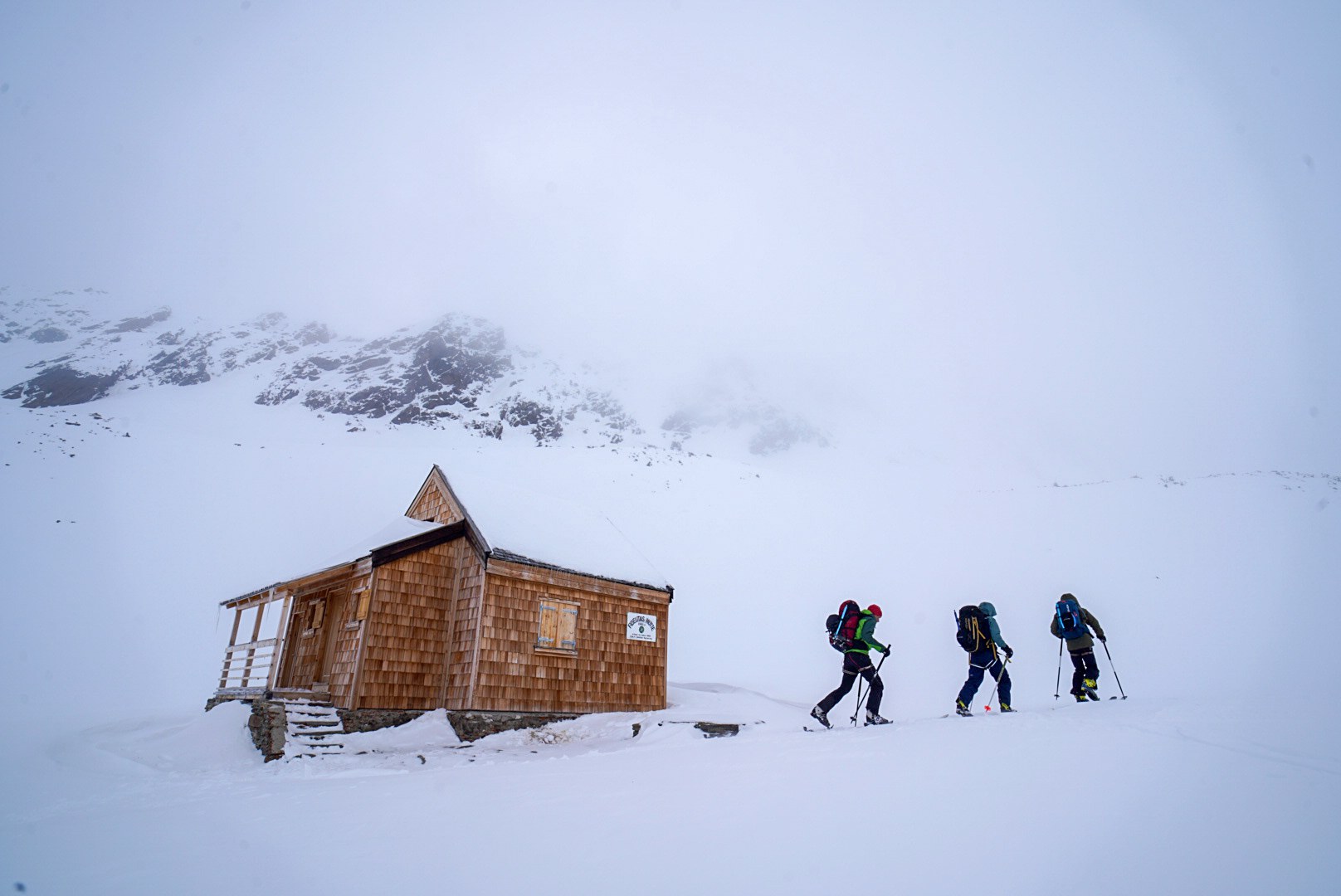Groupe passant devant une petite cabane en bois sous les nuages, étape Fidelitas Hütte – Martin-Busch-Hütte, dans les Alpes de l’Ötztal en Autriche.
