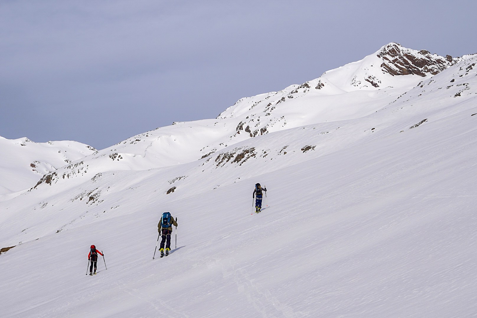 Skieurs suivant la trace sur un vaste versant blanc, étape Martin-Busch-Hütte – Hochjoch Hospiz, dans les Alpes de l’Ötztal en Autriche.