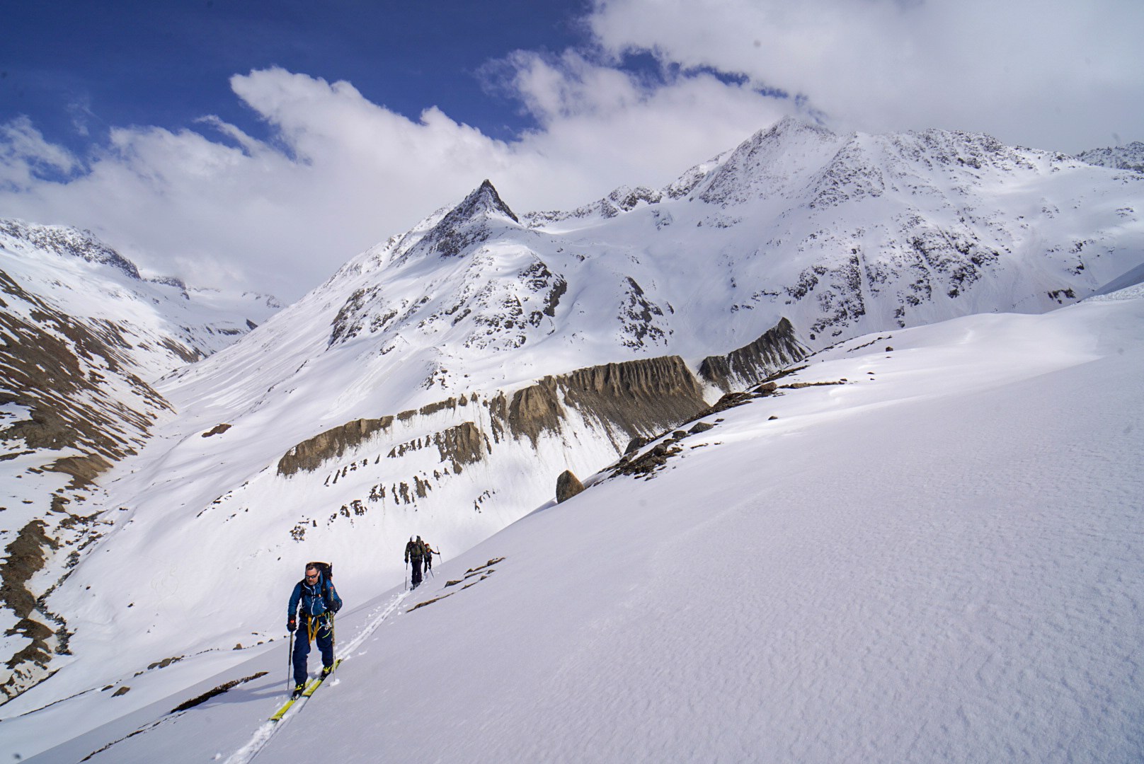 Skieurs progressant dans une haute vallée enneigée, étape Fidelitas Hütte – Martin-Busch-Hütte, dans les Alpes de l’Ötztal en Autriche.