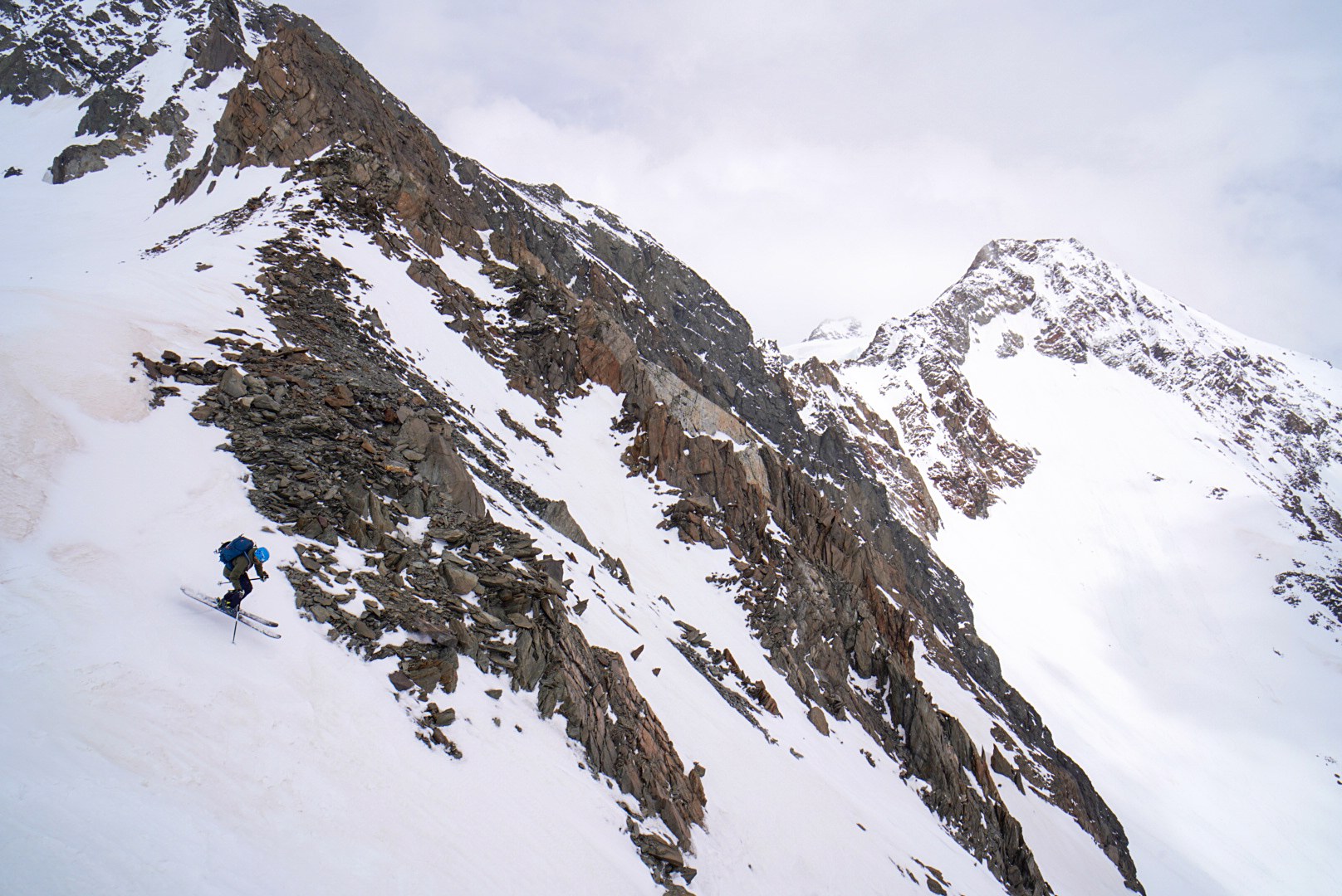 Skieur franchissant un versant neigeux et rocheux, étape Hochjoch Hospiz – Vernagthütte, dans les Alpes de l’Ötztal en Autriche.