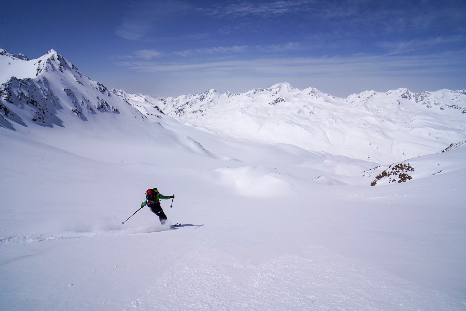 Skieur descendant une combe glaciaire avec les sommets en arrière-plan, étape Martin-Busch-Hütte – Hochjoch Hospiz, dans les Alpes de l’Ötztal en Autriche.