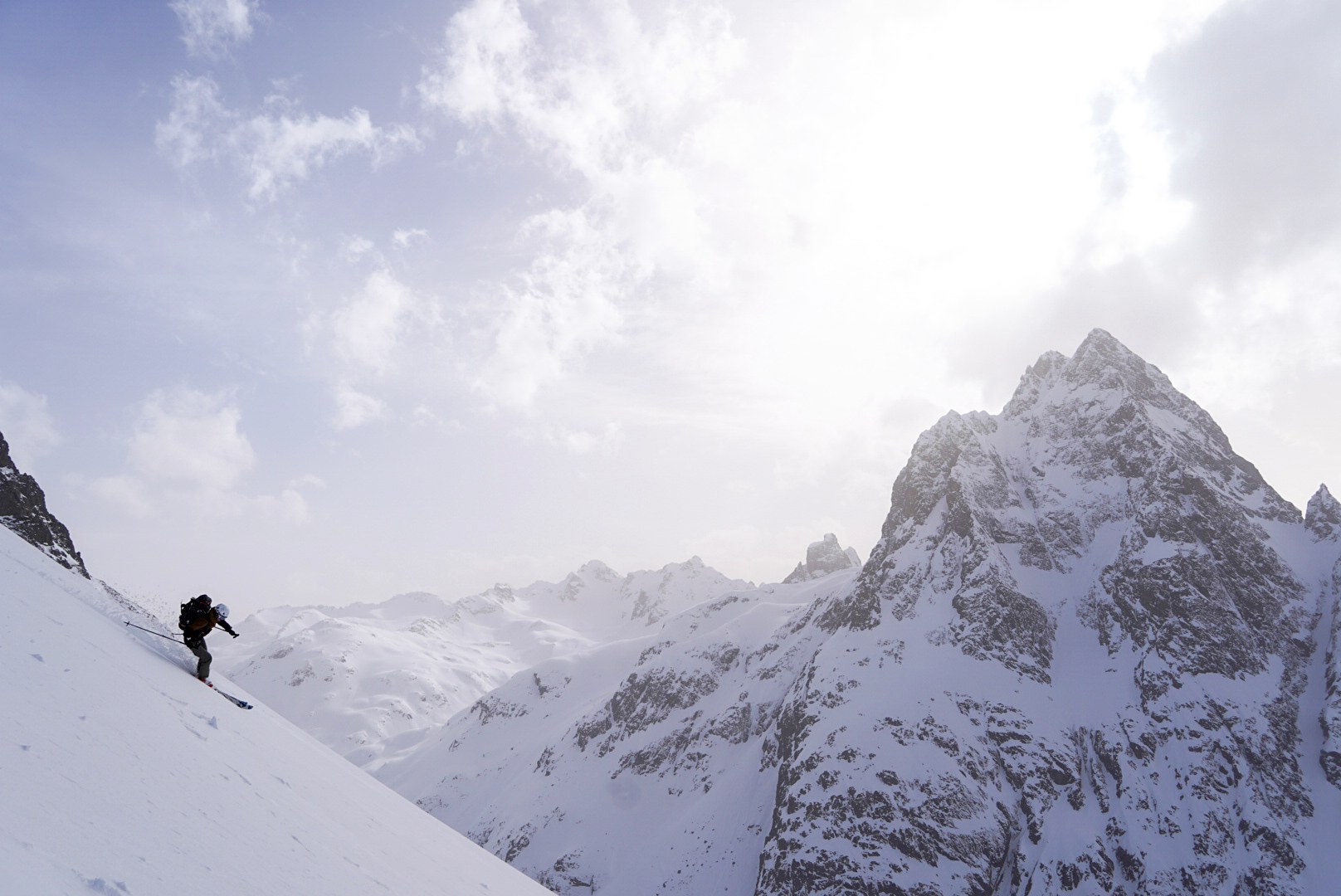 Skieur face à un sommet pyramidal pendant le tour à ski du Verwall au Tyrol, au jour 1 de l’itinérance.