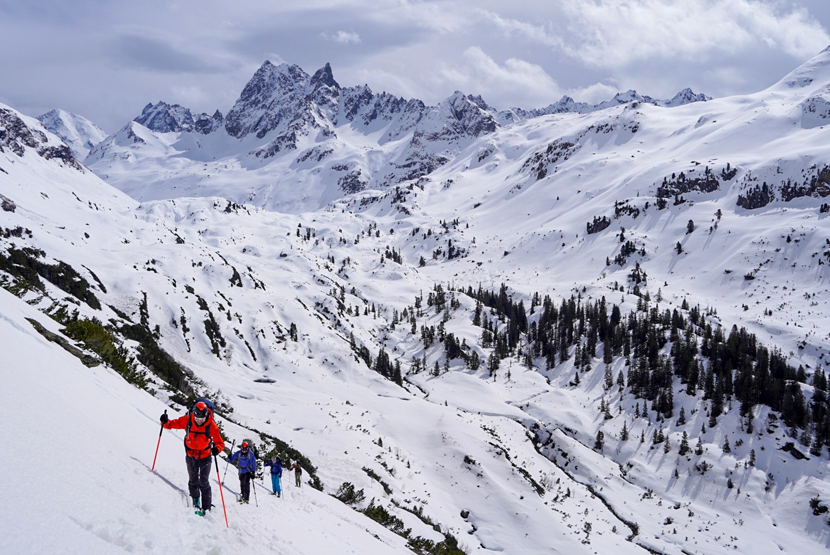 Montée du groupe au-dessus des forêts pendant le tour à ski du Verwall au Tyrol, au jour 3 de l’itinérance.