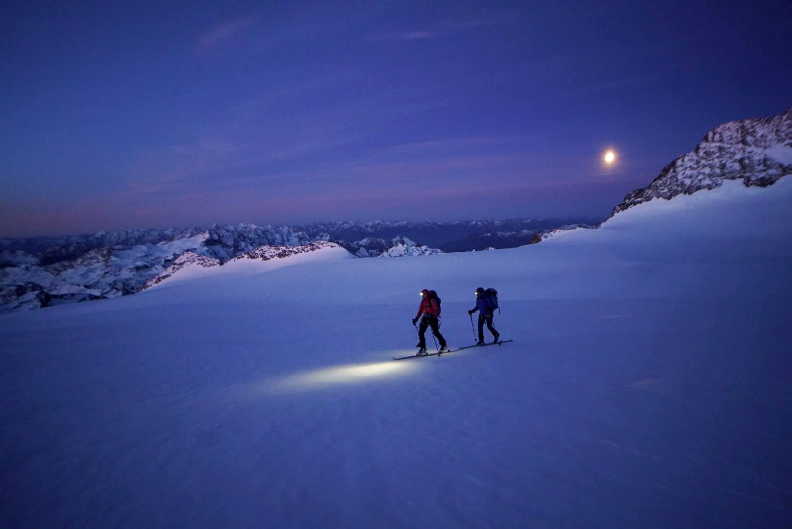 Des alpinistes progressent de nuit sur le glacier.
