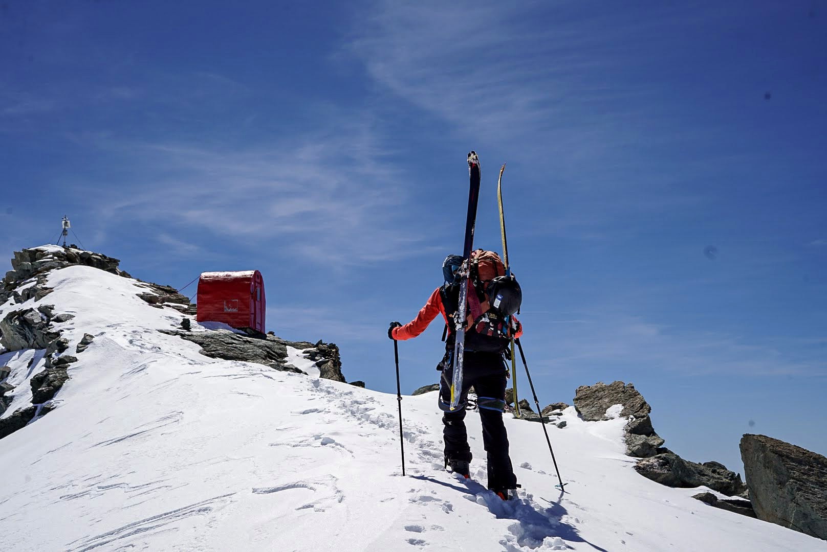 Un skieur rejoint le bivouac par une pente raide.