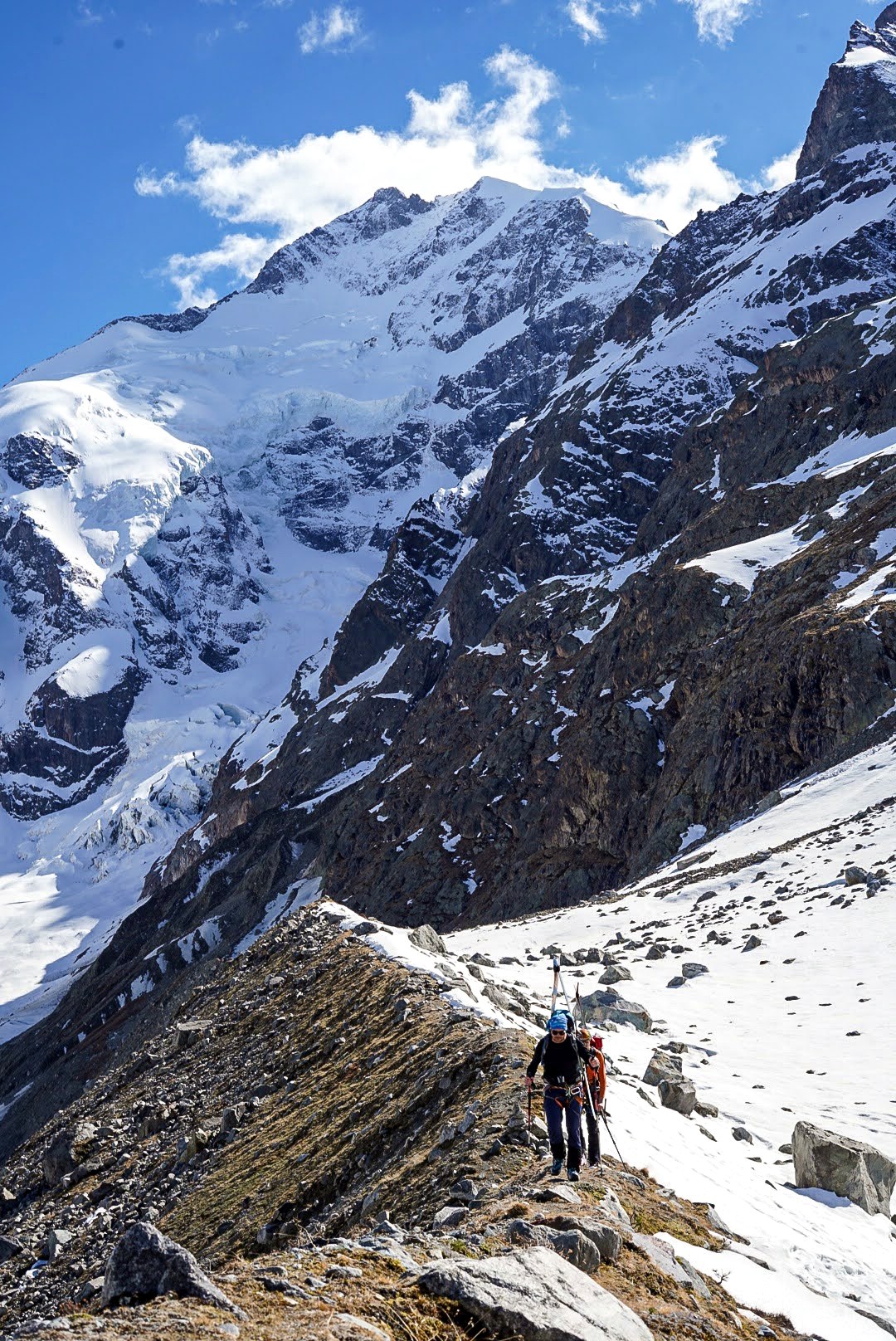 Un skieur traverse une moraine rocheuse au-dessus du glacier.