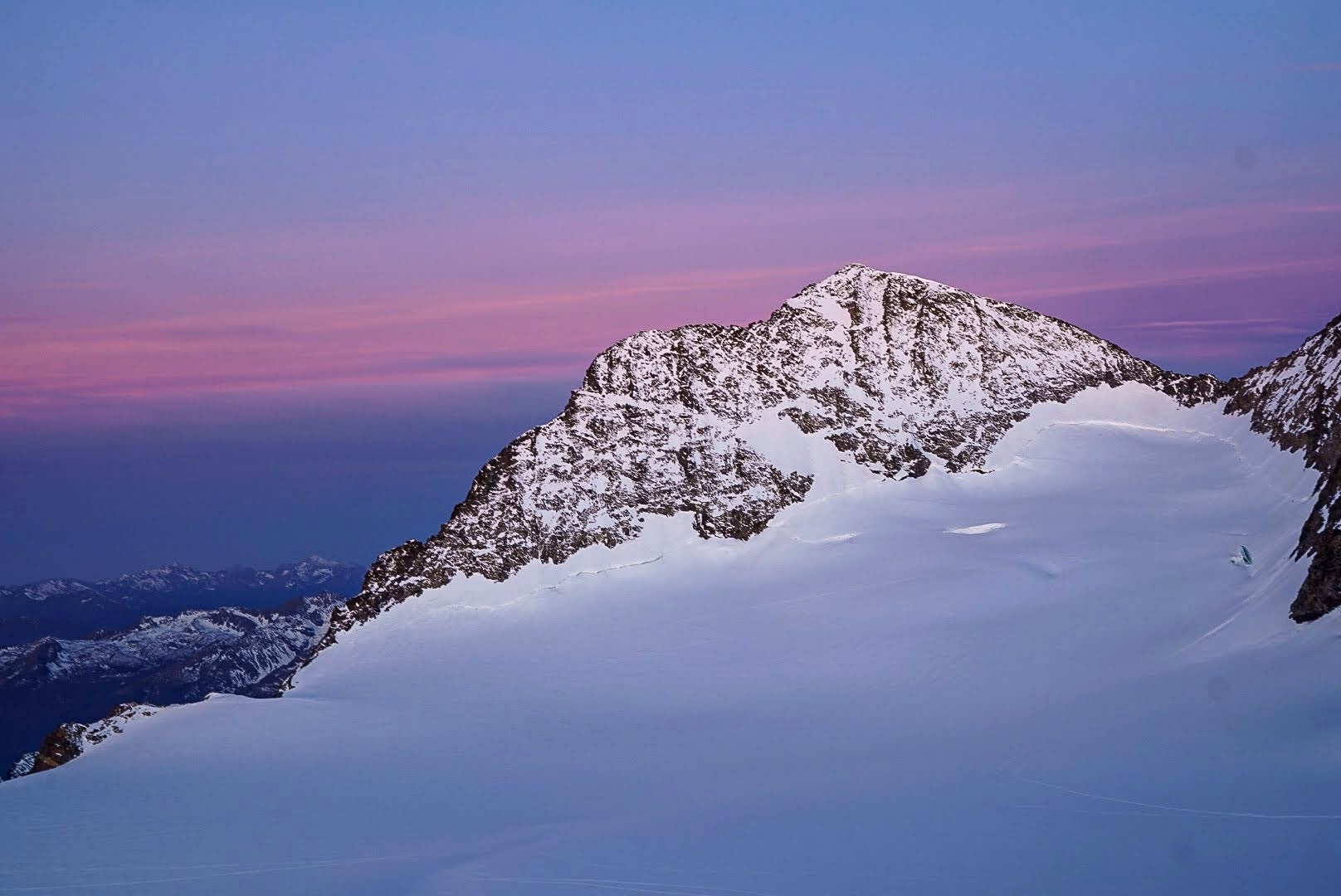 Un ciel rose accompagne les premières lumières sur les sommets.