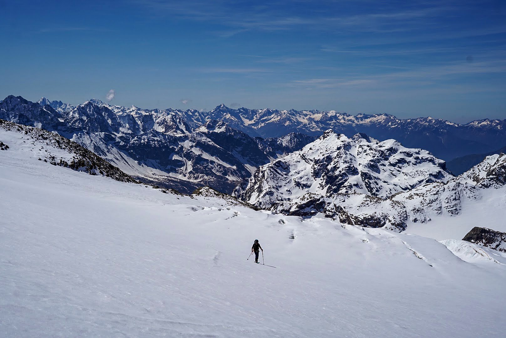 Un alpiniste avance skis sur le sac sur une arête enneigée.