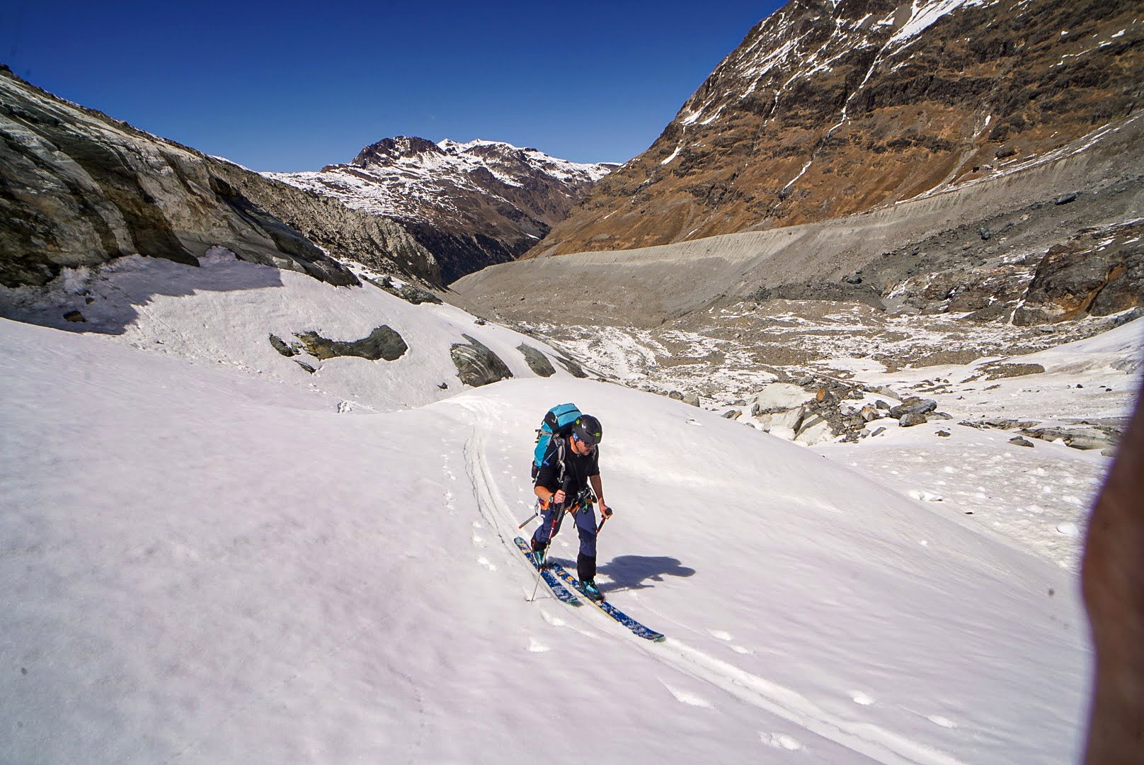 Deux skieurs avancent sur un glacier vaste et crevassé.