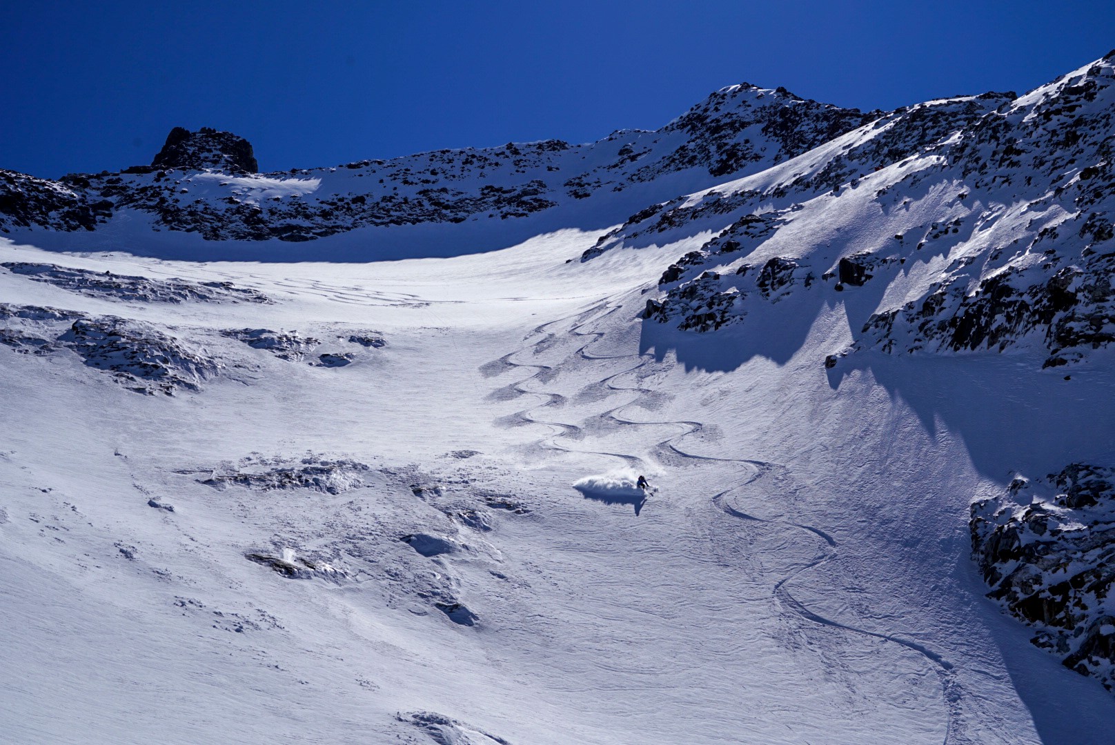 Traces de ski dans une grande pente de neige vierge au pied de barres rocheuses, Dammastock