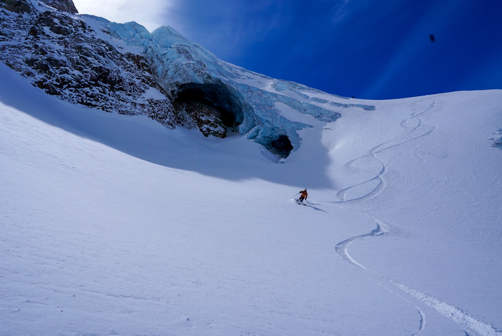Traces de ski sous une grotte de glace ouverte dans un front de glacier, Dammastock