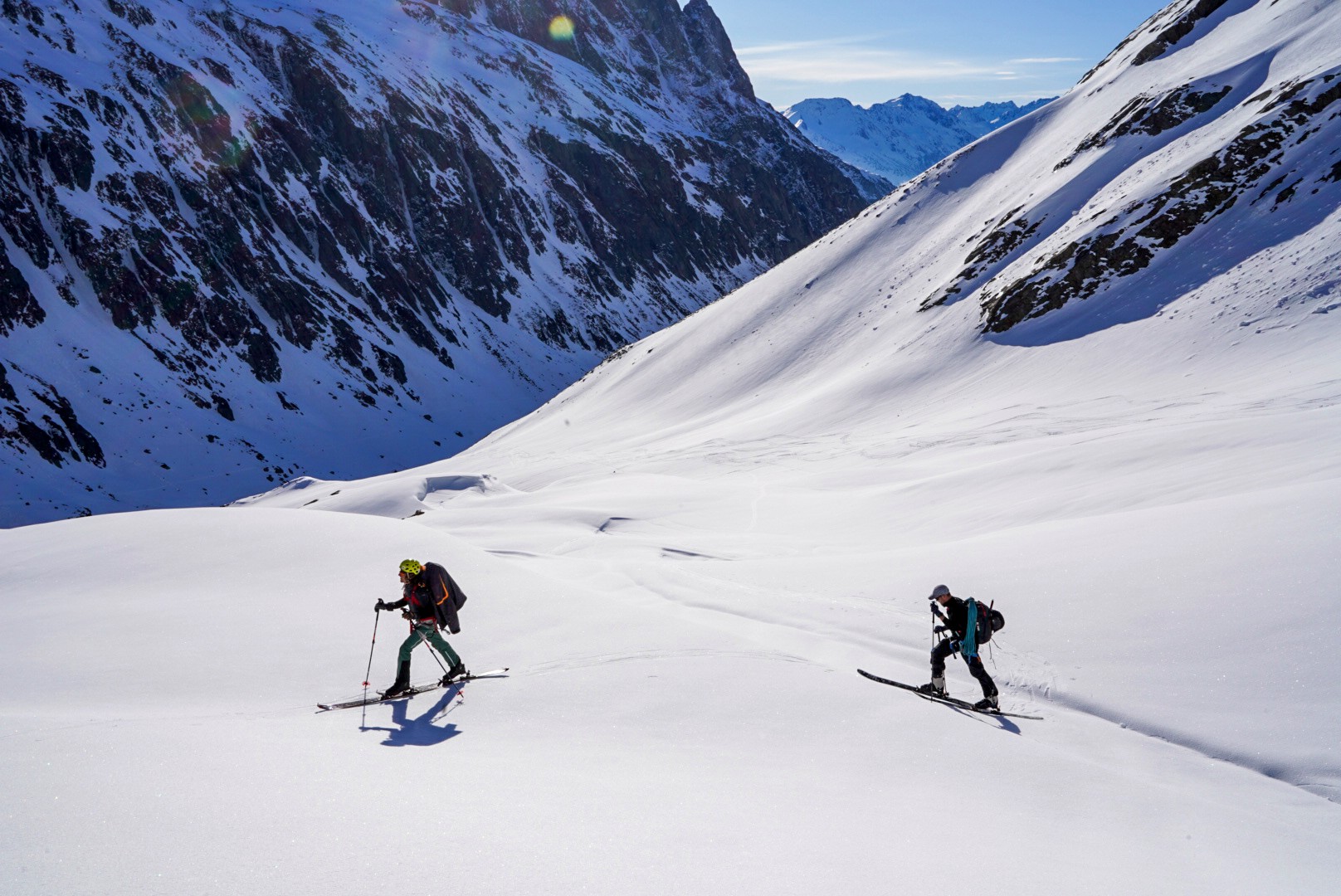 Deux skieurs dans un vallon enneigé au pied de parois rocheuses, Dammastock