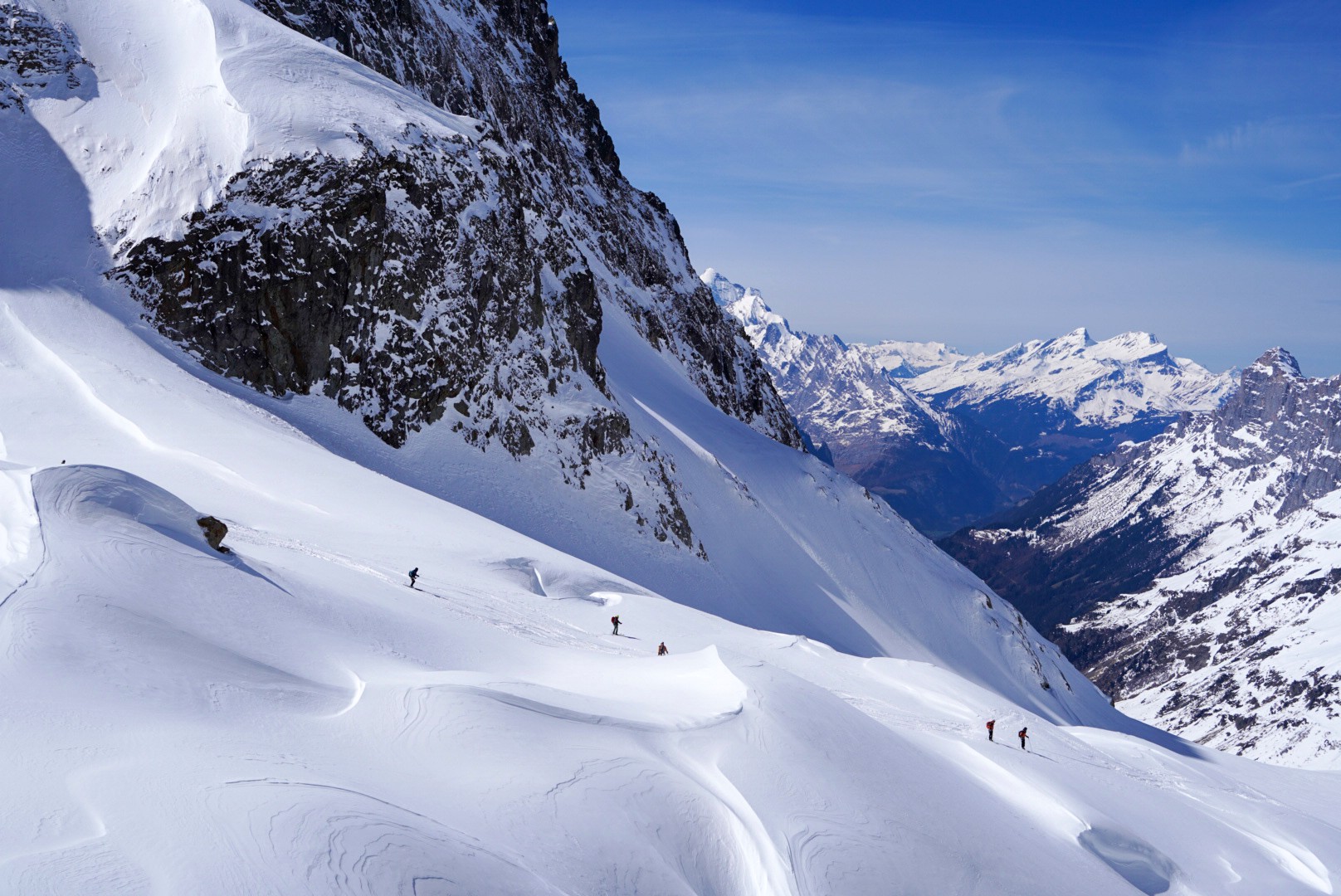 File de skieurs sous une paroi rocheuse, glacier et vallée au fond, Dammastock