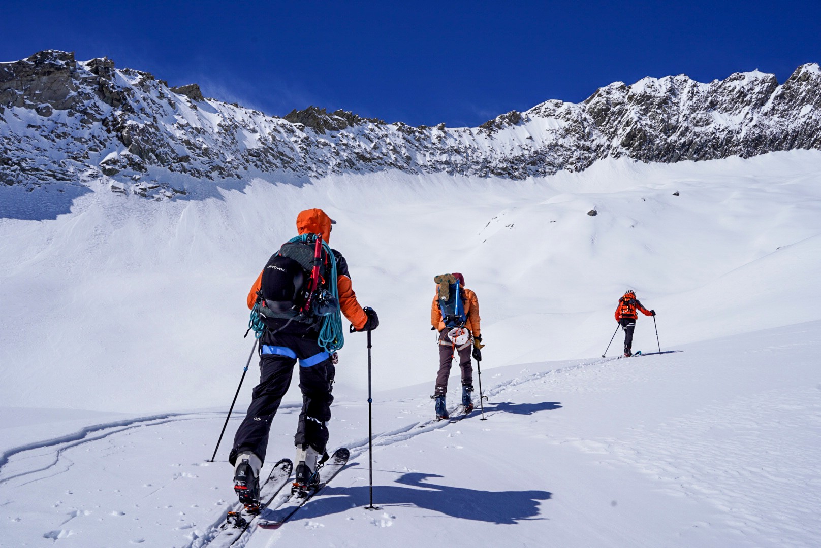 Groupe de skieurs en montée sur un glacier sous un ciel bleu, traversée du Dammastock
