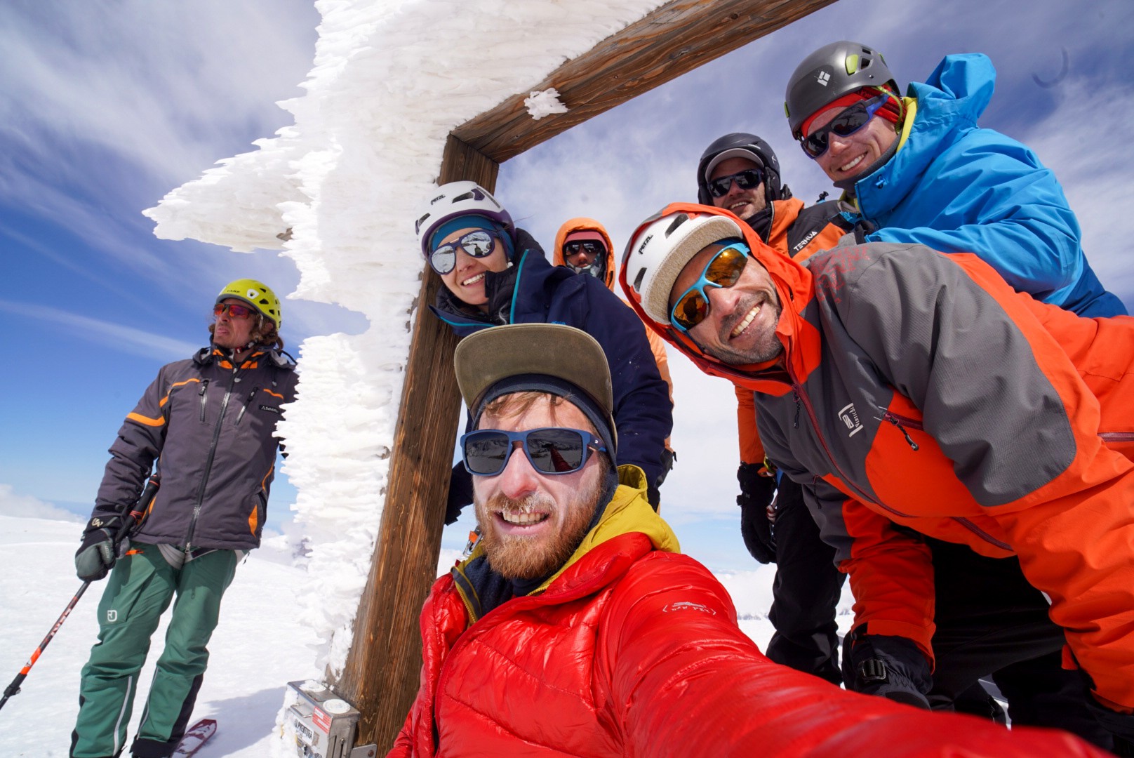 Photo de groupe souriante à travers un cadre en bois givré, casques et lunettes de soleil