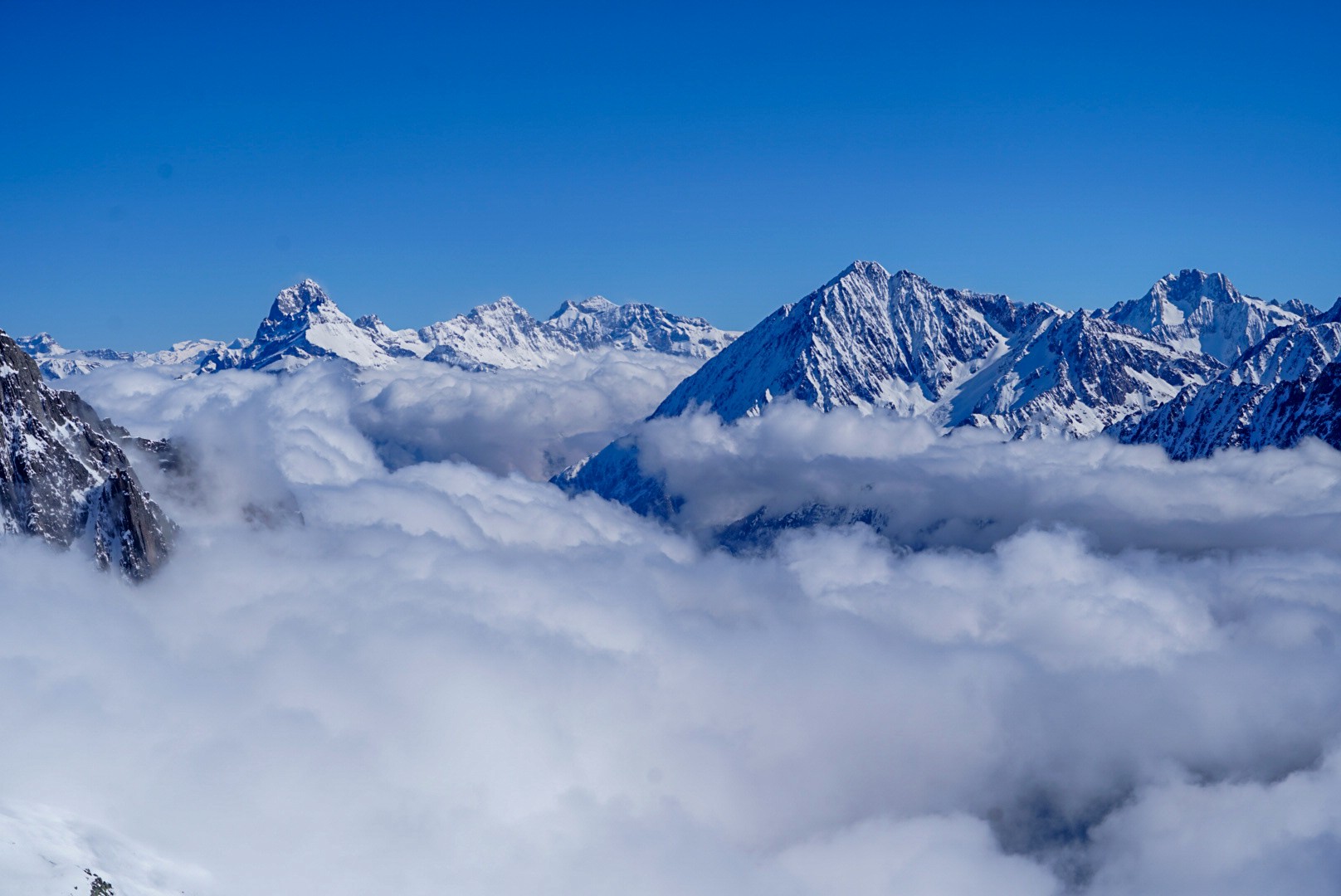 Mer de nuages et sommets enneigés sous un ciel bleu, vus depuis l'itinéraire du Dammastock