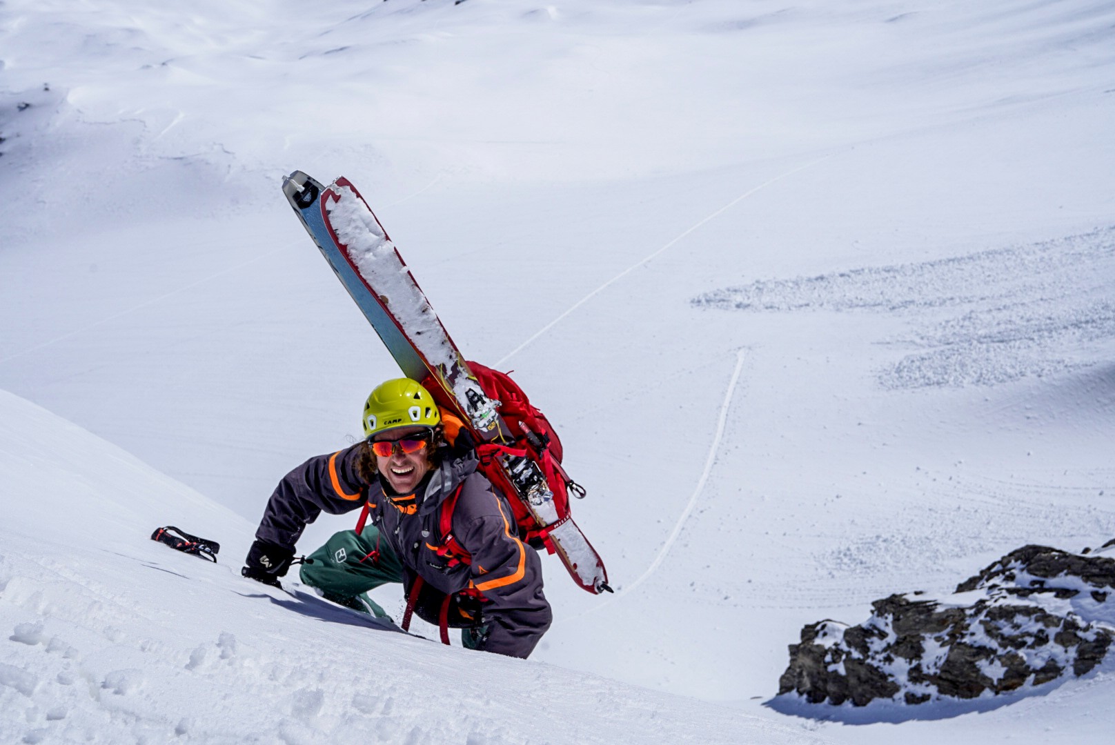 Skieur casqué grimpant une pente de neige, skis sur le sac, traversée du Dammastock