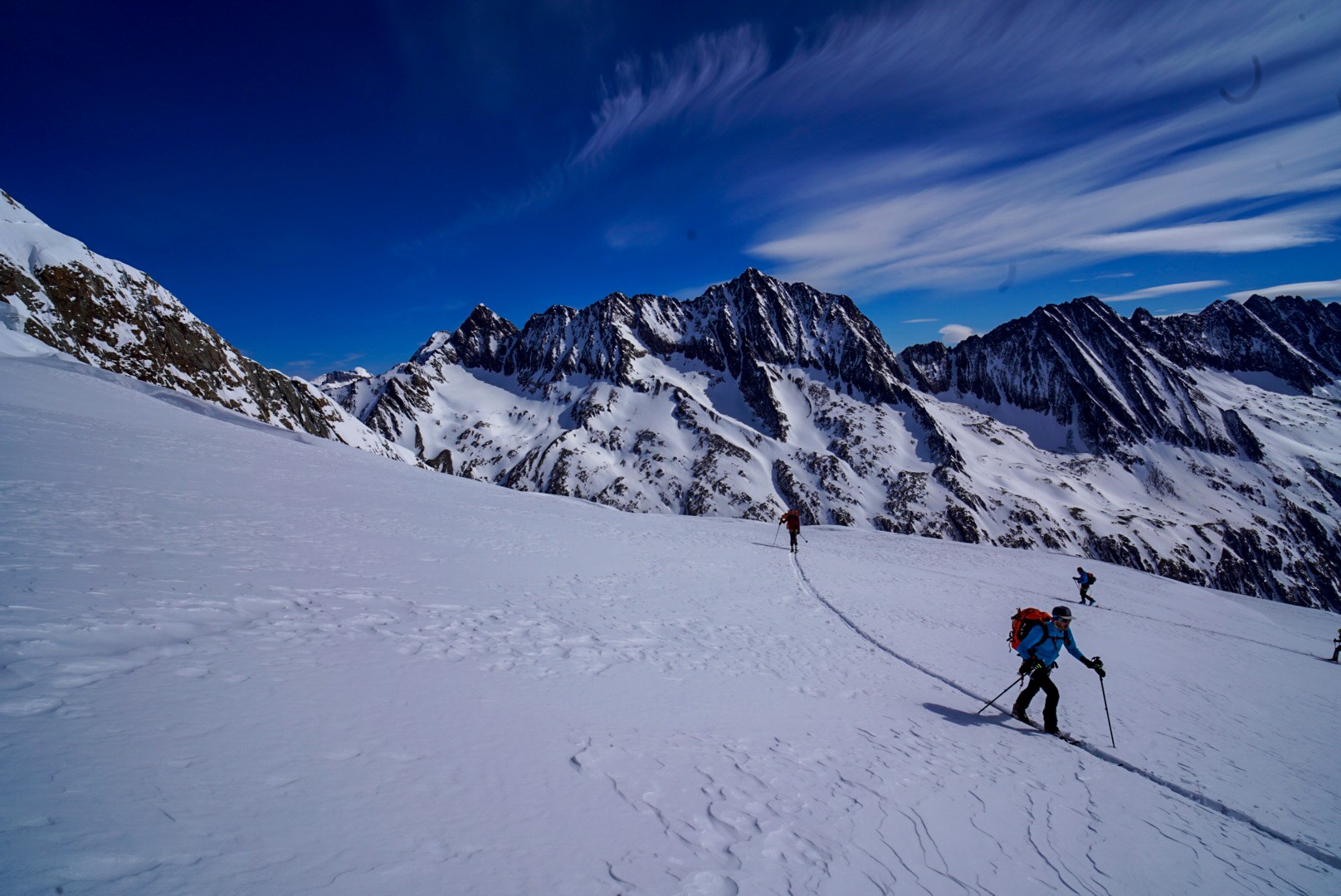 Skieur remontant un glacier face à une chaîne de sommets déchiquetés, ciel de cirrus, Dammastock