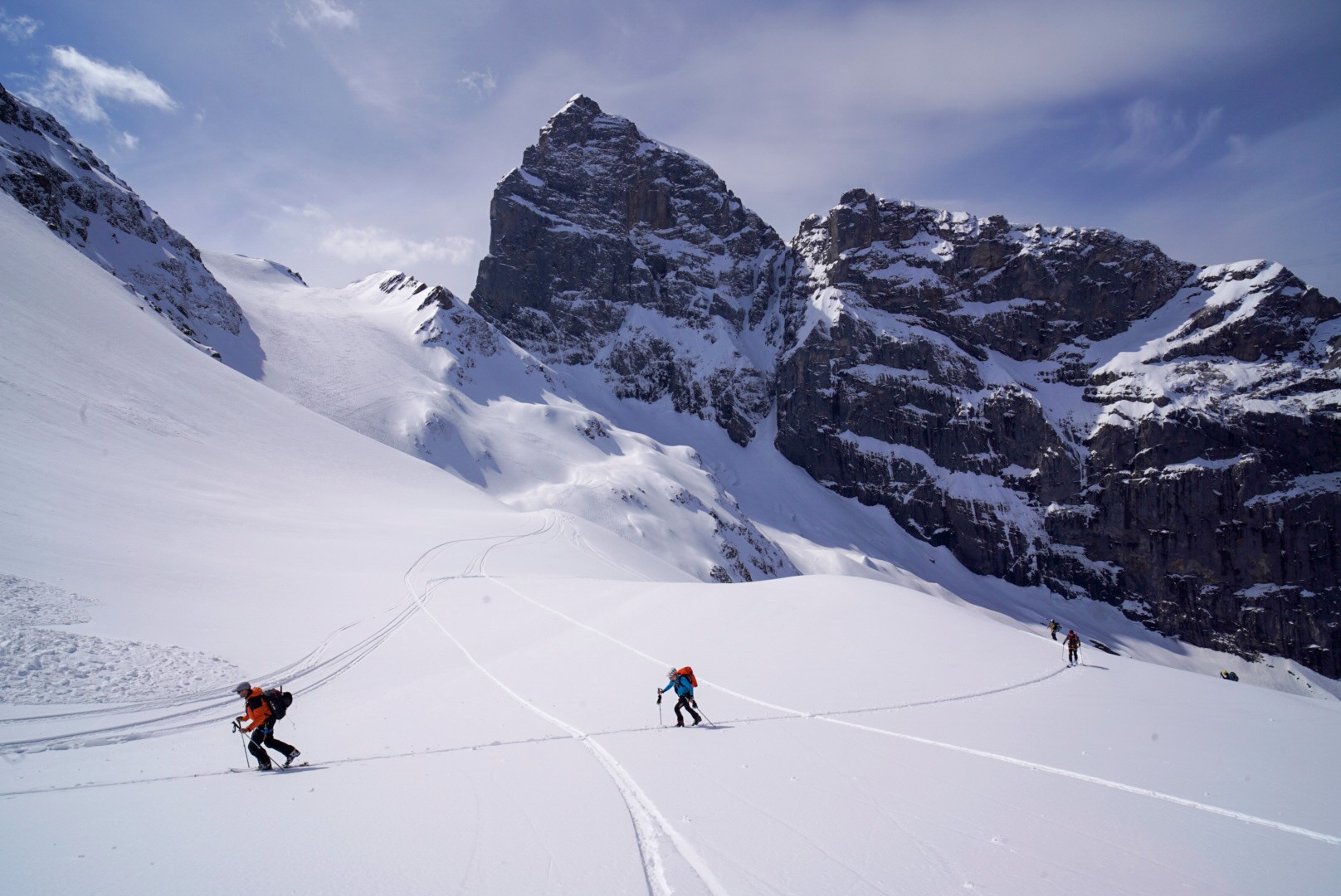 Skieurs sur un glacier face à un sommet rocheux massif, Dammastock