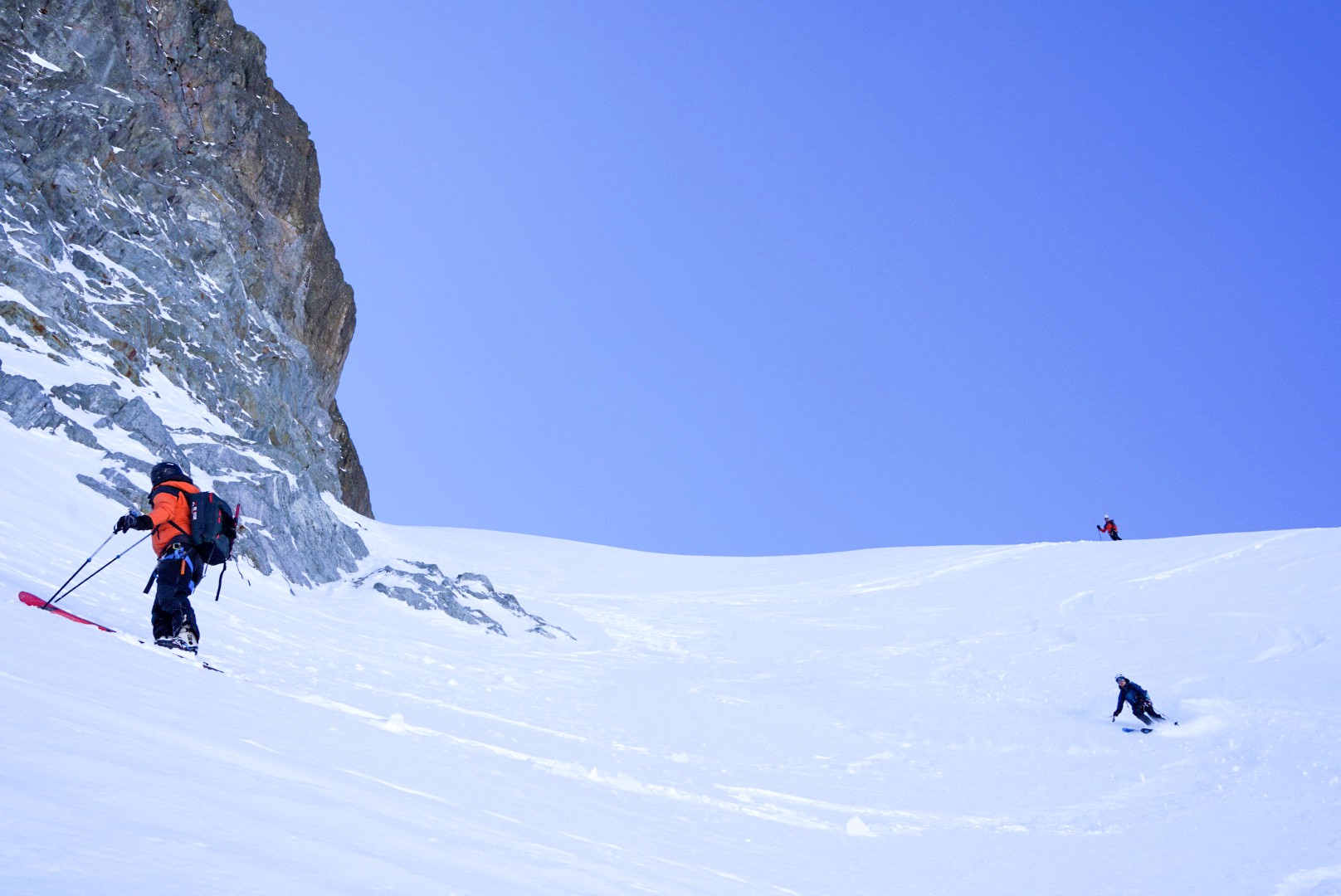 Skieur sous une falaise, ciel bleu intense, Dammastock