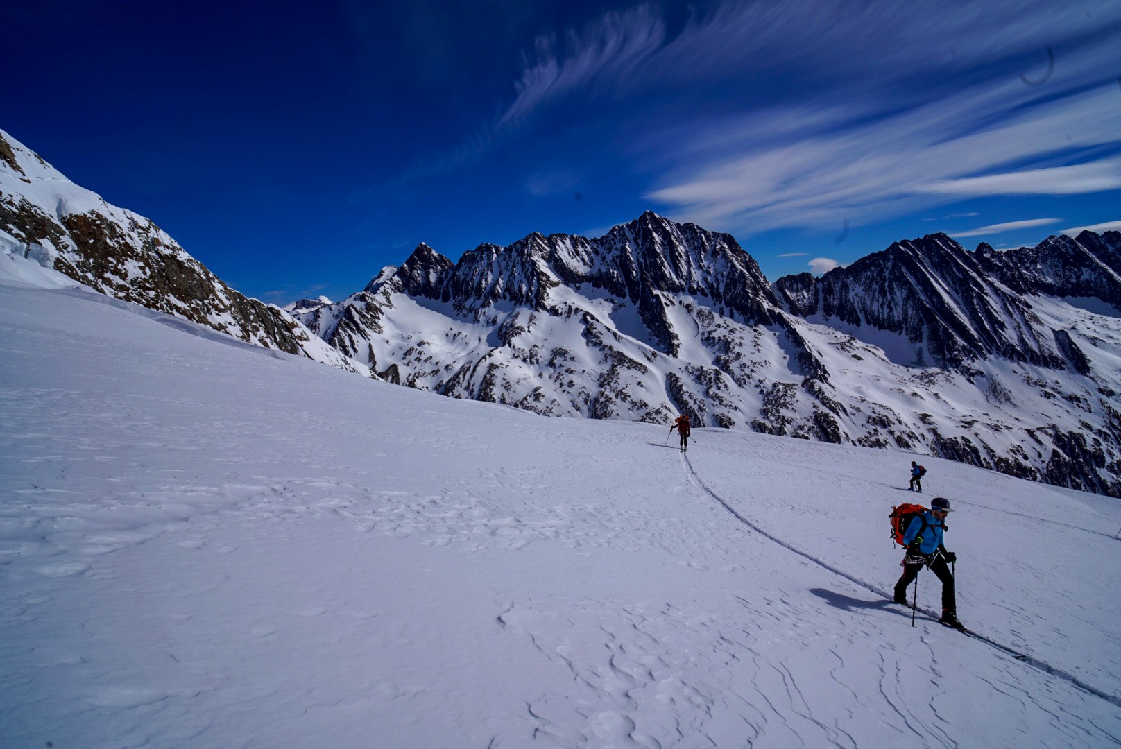 Skieur en montée sur un glacier, longue trace dans la neige, crêtes enneigées au fond, Dammastock