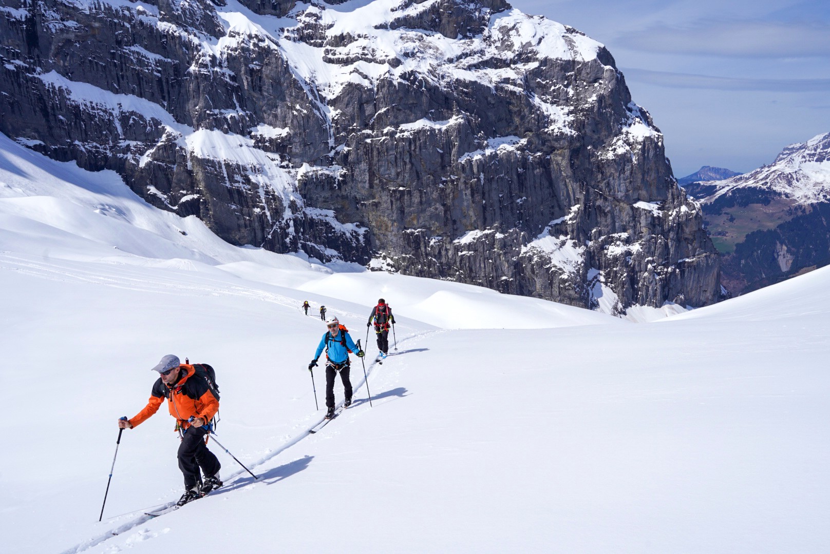 Groupe de skieurs de randonnée sur un glacier face à de hautes parois rocheuses, Dammastock