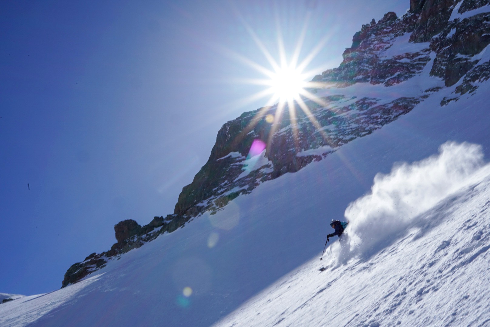Skieur soulevant la poudreuse à contre-jour, soleil en étoile au-dessus d'une arête, Dammastock