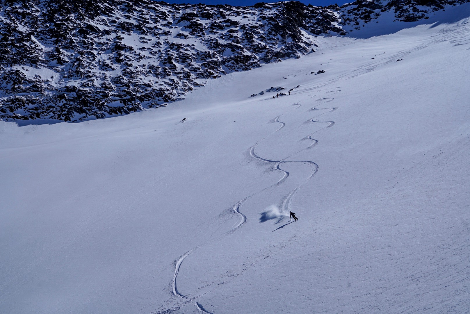 Traces de virages dans une vaste pente de poudreuse vierge, un skieur en bas, Dammastock